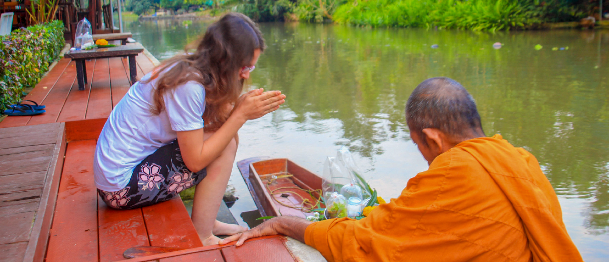 Backpacker offering alms to a monk at a riverside templeBackpacking group participating in a water fight with colorful water guns during a local festival