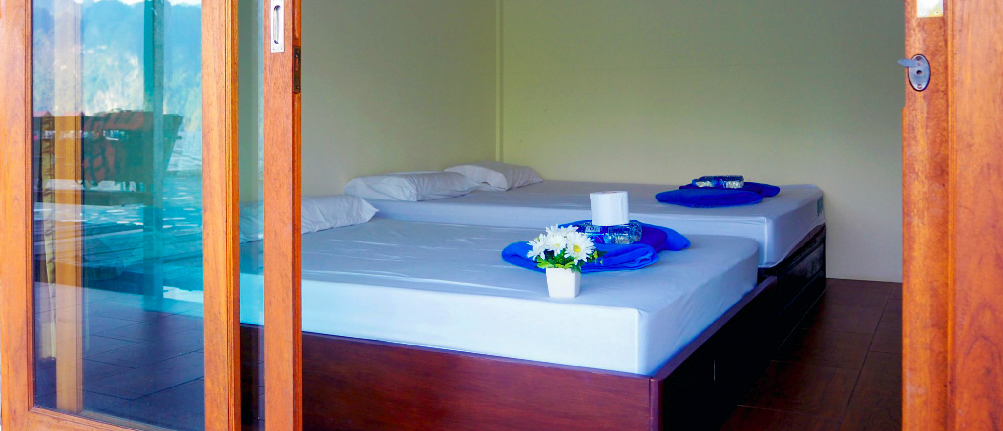 Cozy floating bungalow room with a blue bed and towel art on Cheow Lan Lake