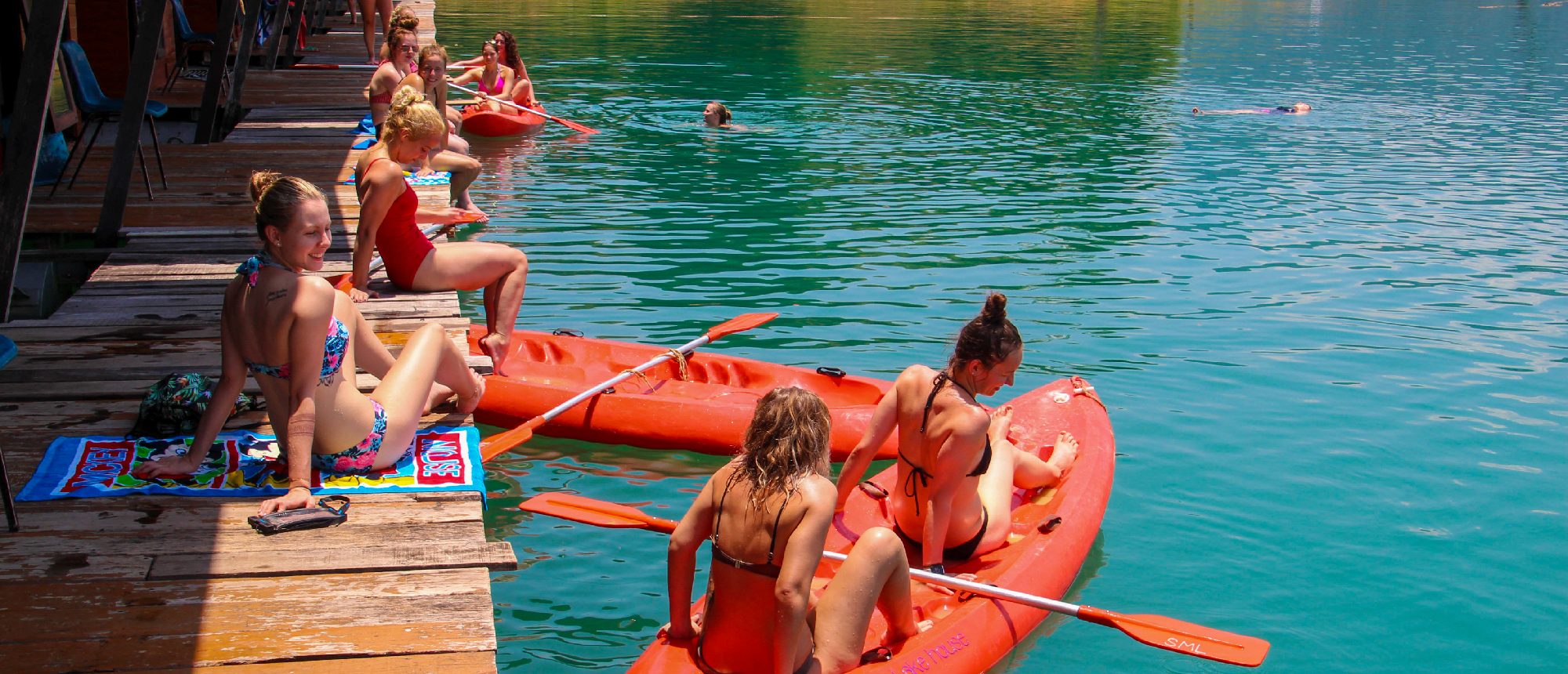 Backpacking group relaxing on a floating dock with drinks on Cheow Lan Lake