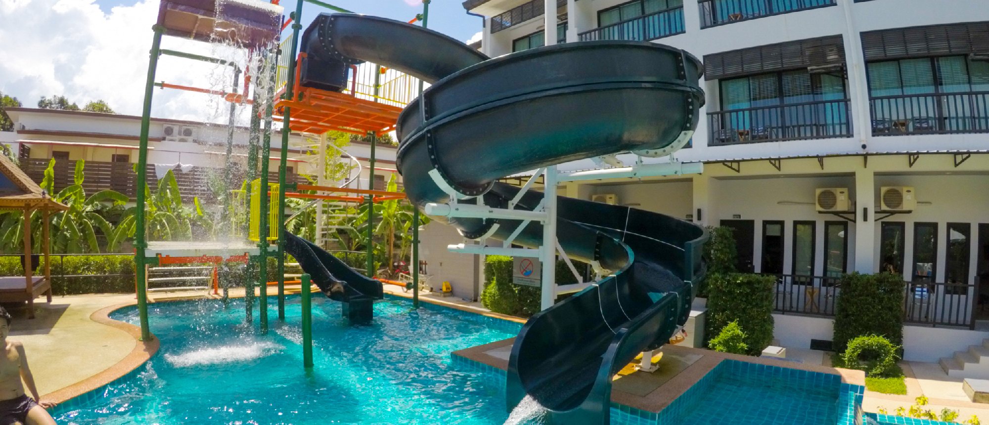 Resort swimming pool with a large water slide and lounge chairs in Ao NangModern hotel room with double bed and floor-to-ceiling windows in Ao Nang
