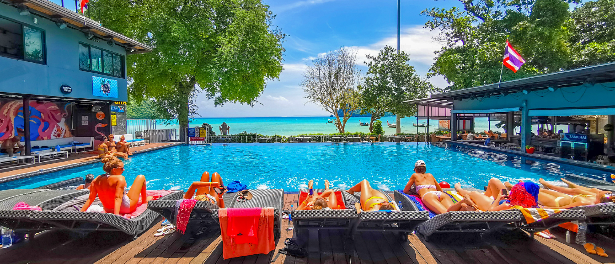 Resort swimming pool with red sun loungers and pool bar on Koh Phi Don
