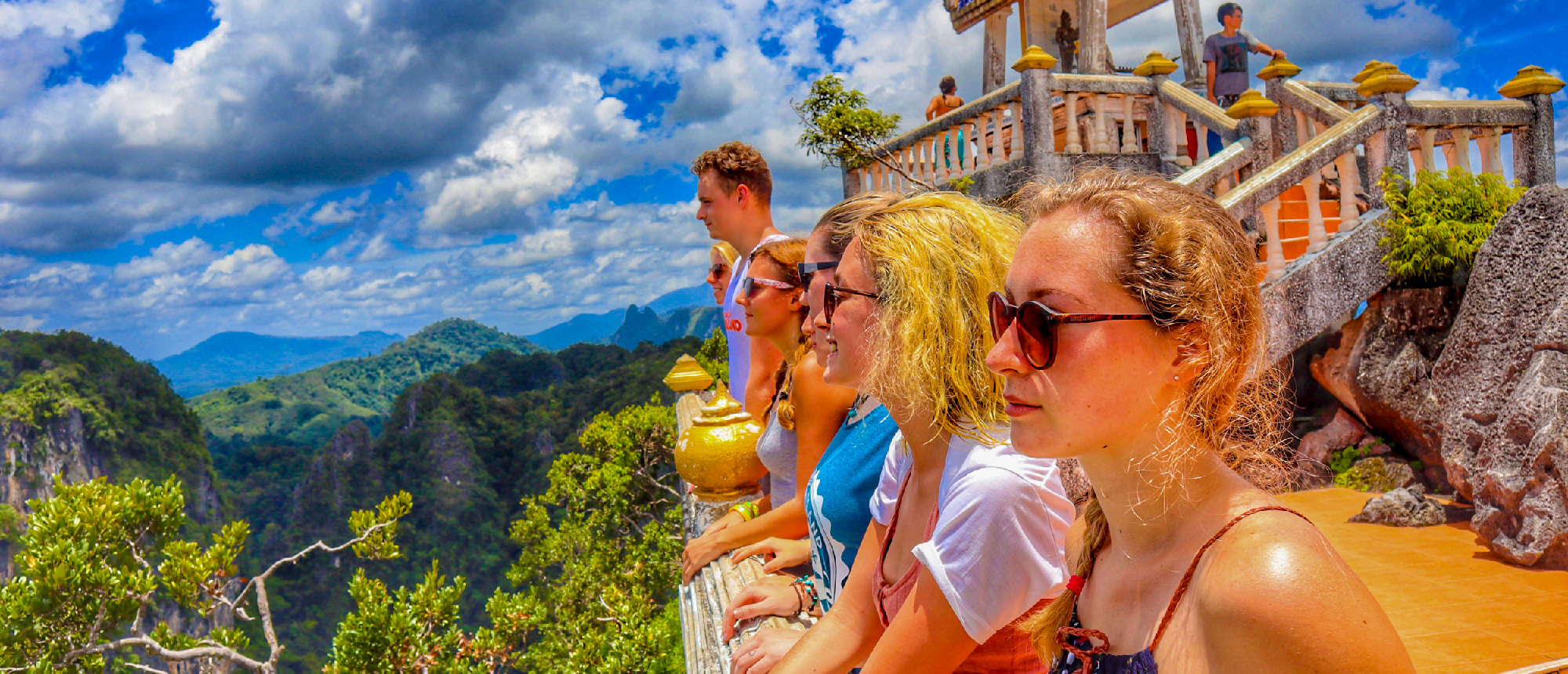 Backpacking group taking a selfie at a hilltop viewpoint with a monkey and panoramic views of the valley