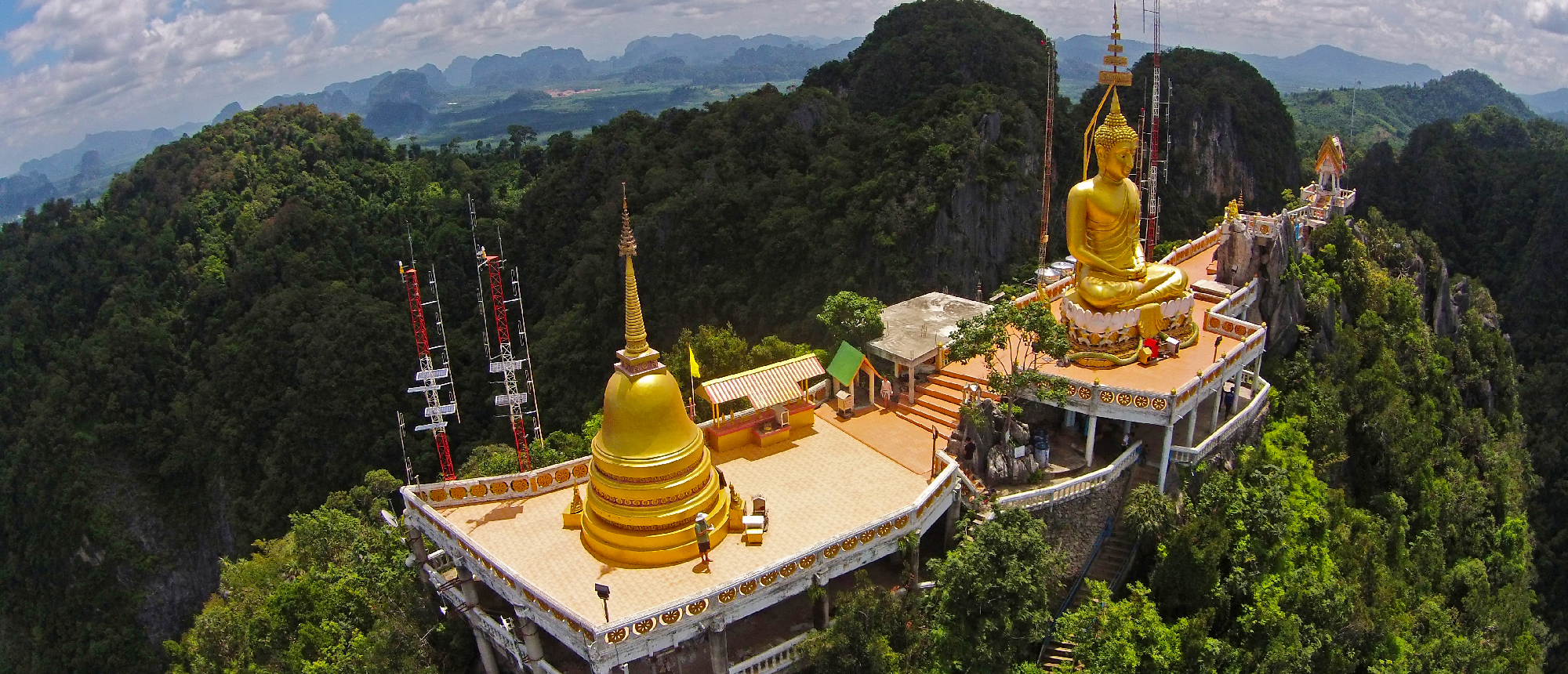 Aerial view of Tiger Cave Temple golden pagoda on a hilltop surrounded by lush green mountains