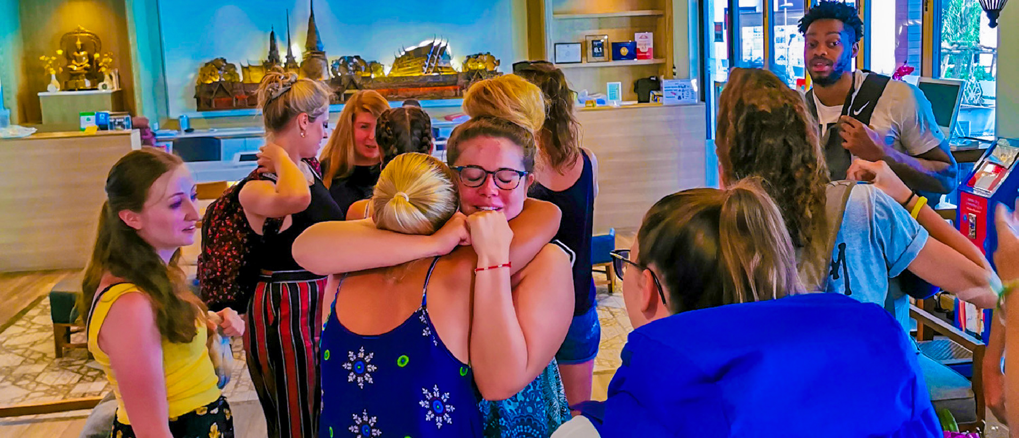 Backpacking group giving farewell hugs at a lively bar in Phuket