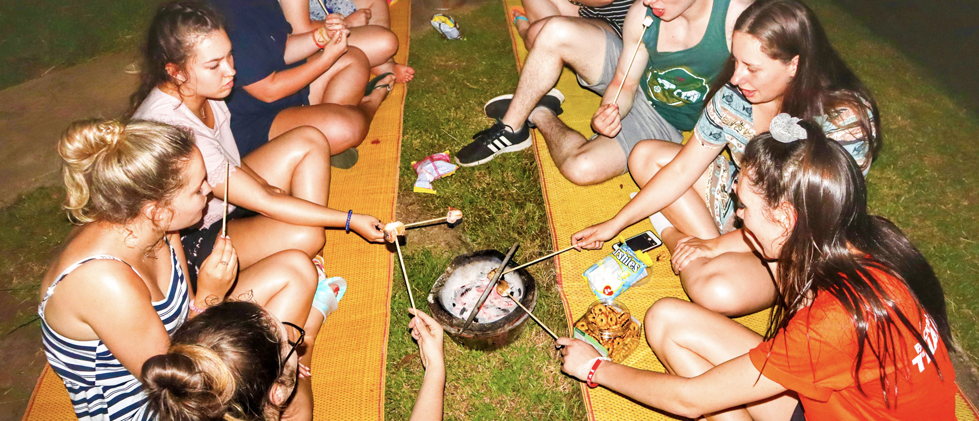Backpacking group enjoying a barbecue picnic at a riverside campsite