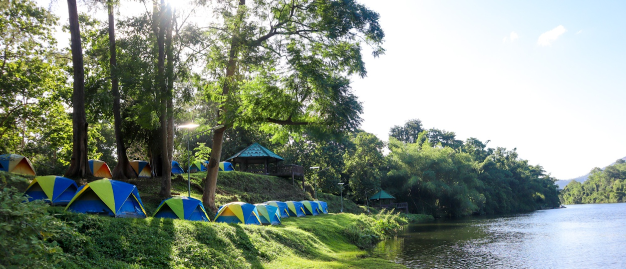 Riverside campsite with blue tents along the Khwae Yai RiverBackpacking group enjoying a barbecue picnic at a riverside campsite