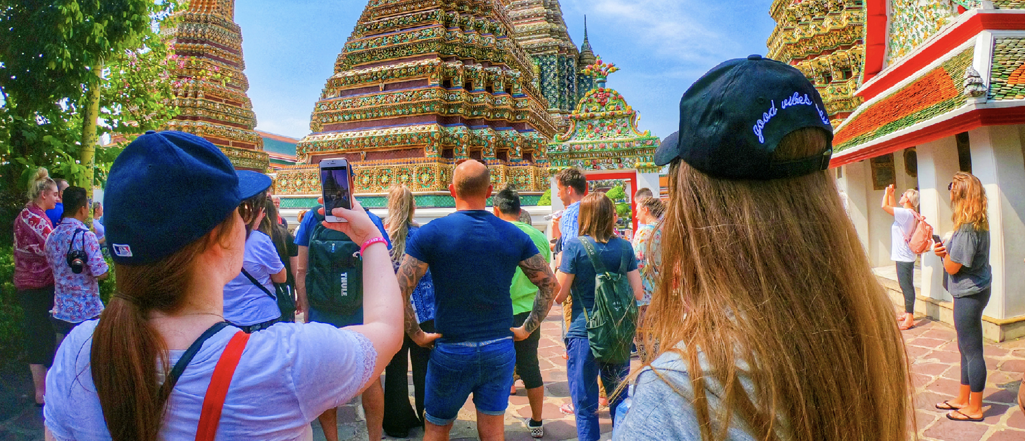 Backpacking group walking toward Wat Arun temple along the Chao Phraya River