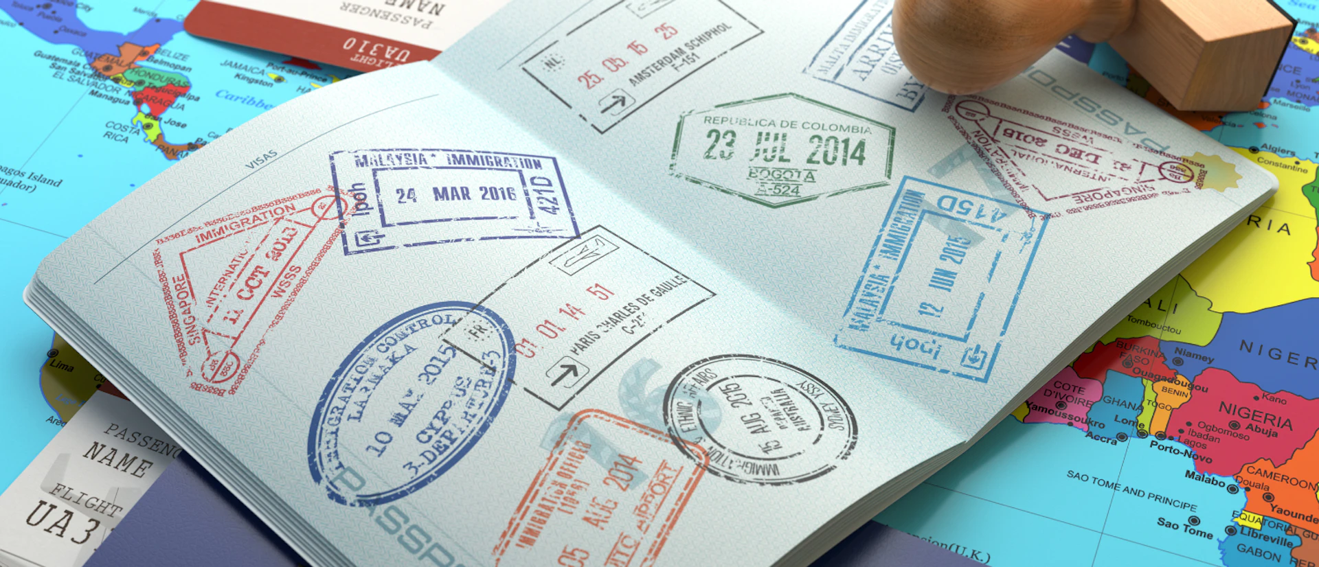An open passport with colorful visa stamps from Malaysia, Singapore, and Colombia, placed on a world map.