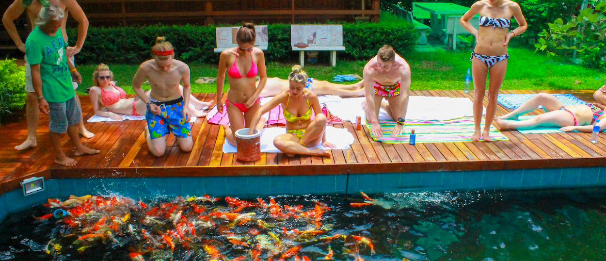 Backpacking group sitting on the floor preparing Thai dishes with local hosts during a cooking class