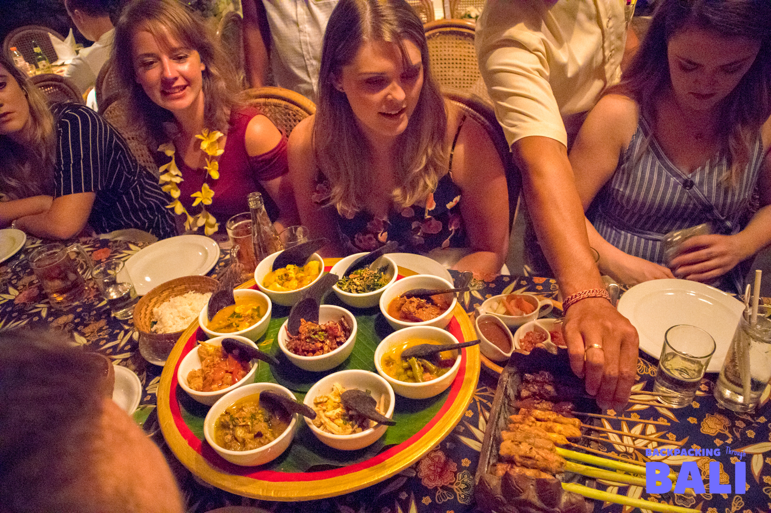Backpacking group sharing Balinese dinner together at a long table