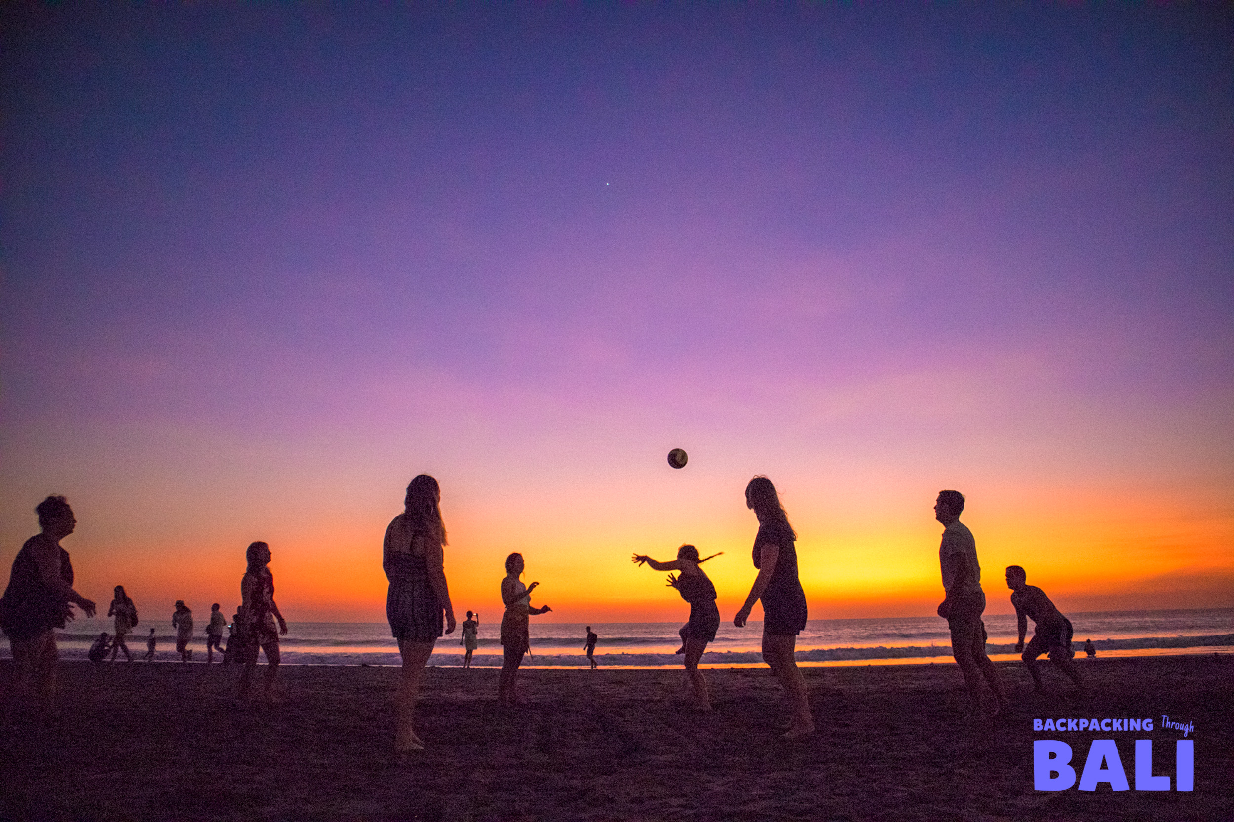 Silhouettes playing ball on the beach at sunset