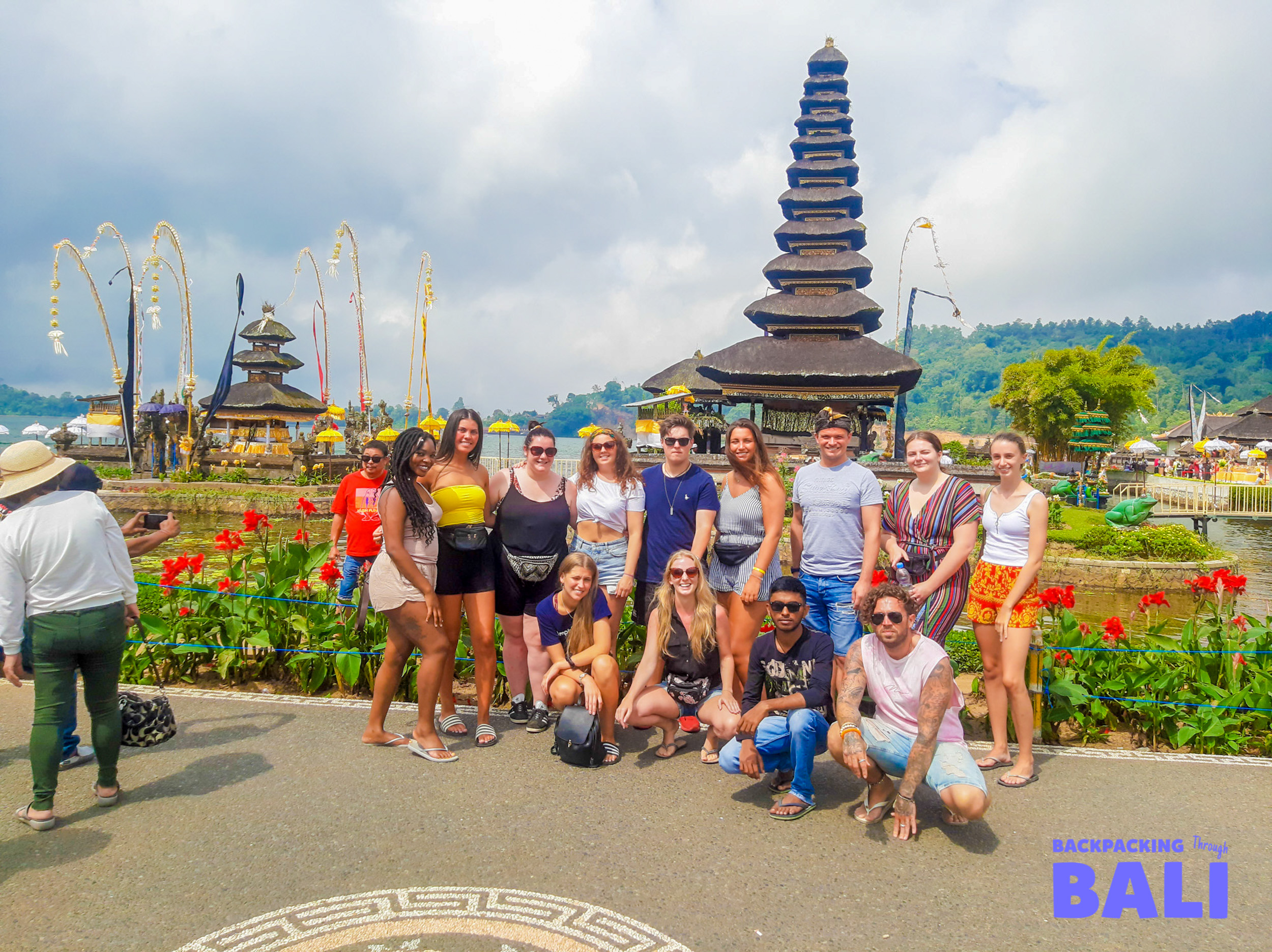 Backpacking group posing in front of Ulun Danu Beratan Temple and flower garden