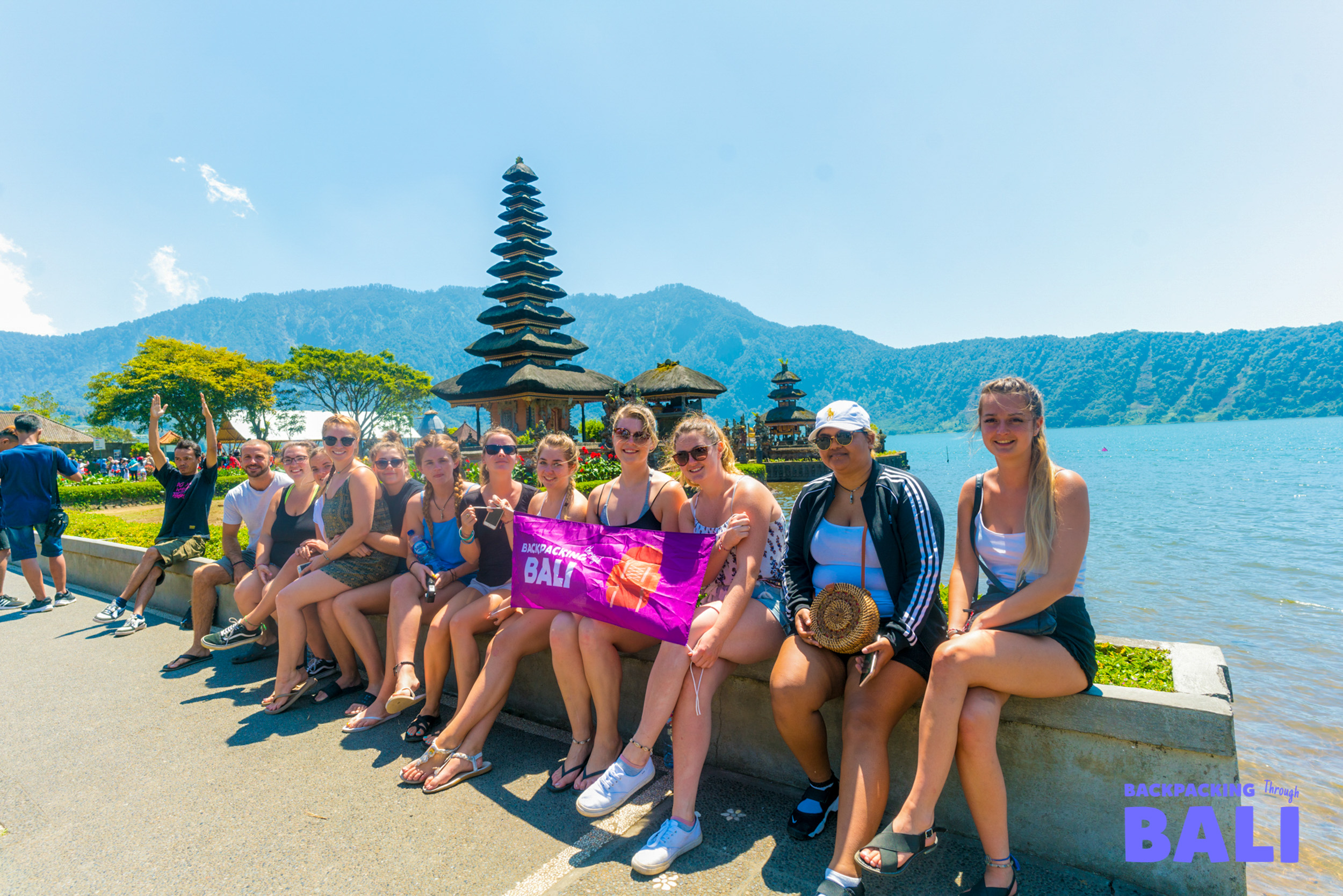 Backpacking group posing together by a lake and mountain view in Bali