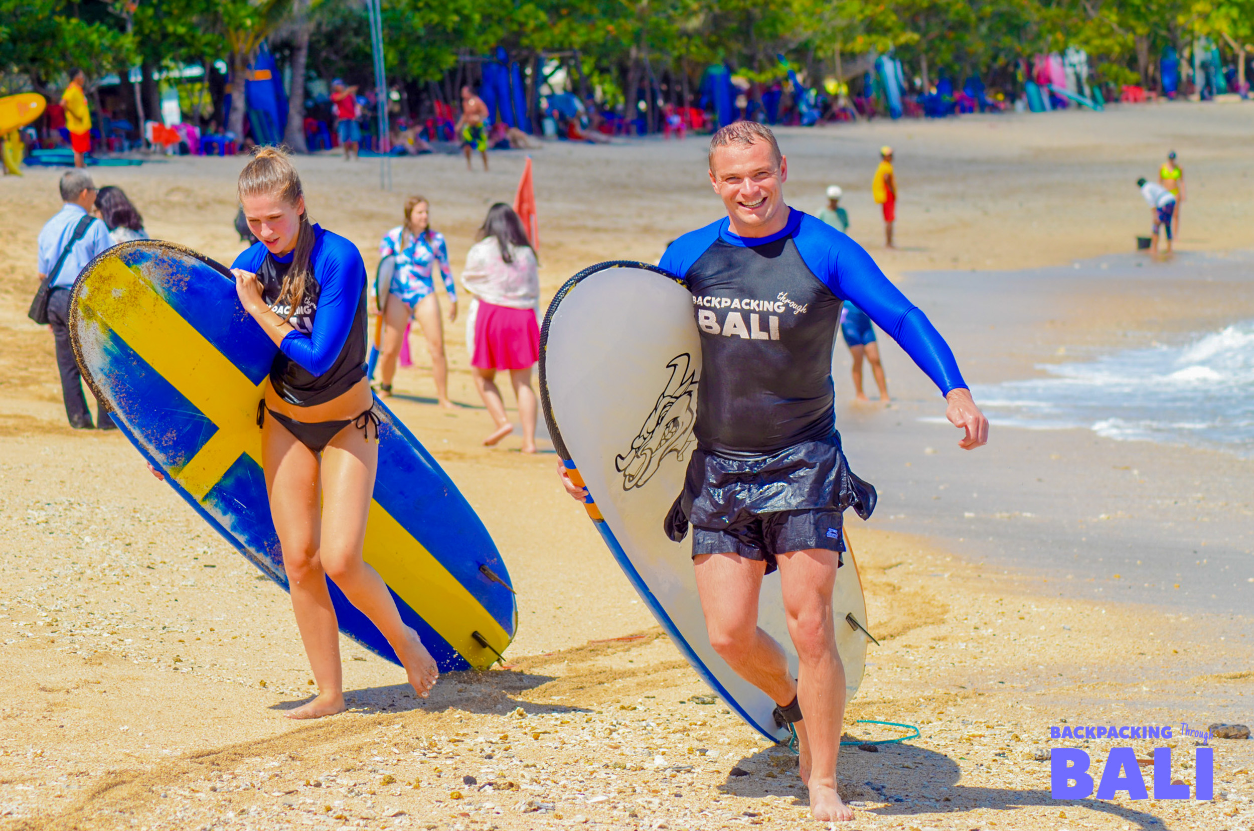 Two travelers learning to surf on small waves at a Bali beach