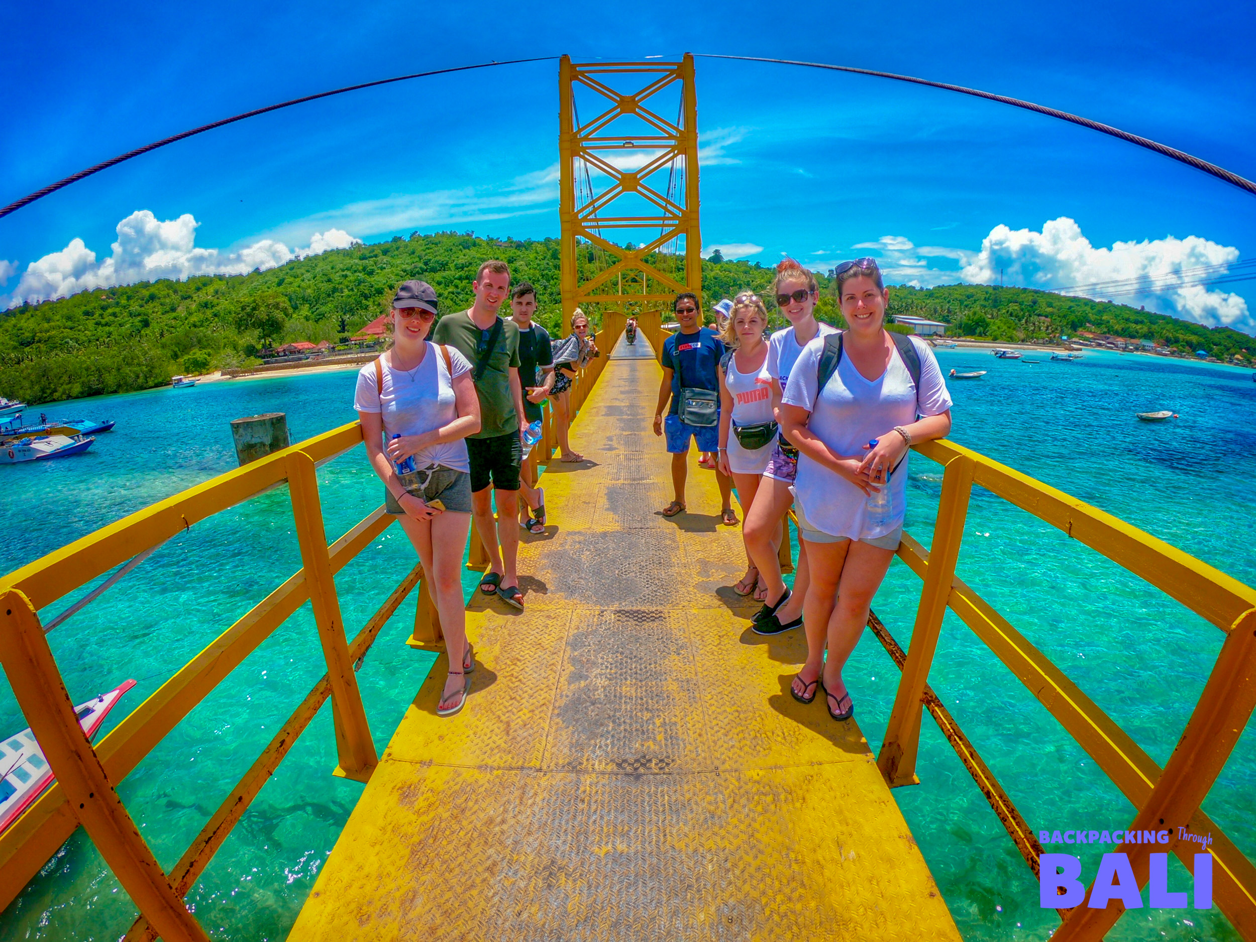 Backpacking group crossing the Yellow Bridge in Nusa Lembongan