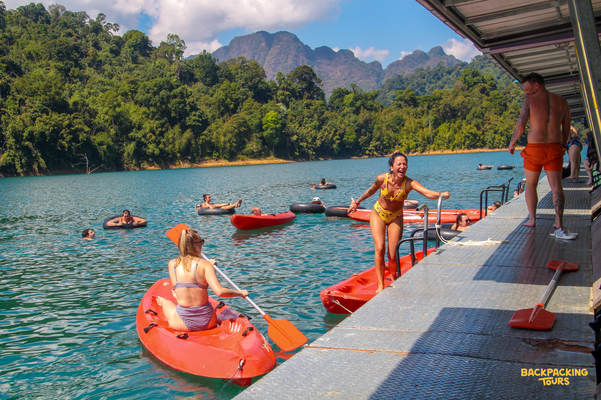 Kayakers on a turquoise lake near floating bungalows with mountains in the background, Day 8 accommodation