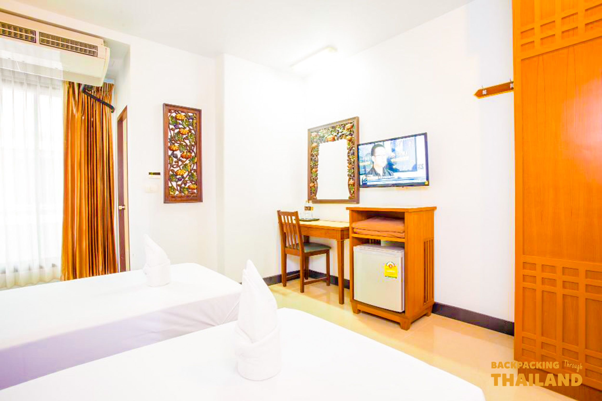 Modern hotel room with a double bed, orange wardrobe, and large window in Bangkok