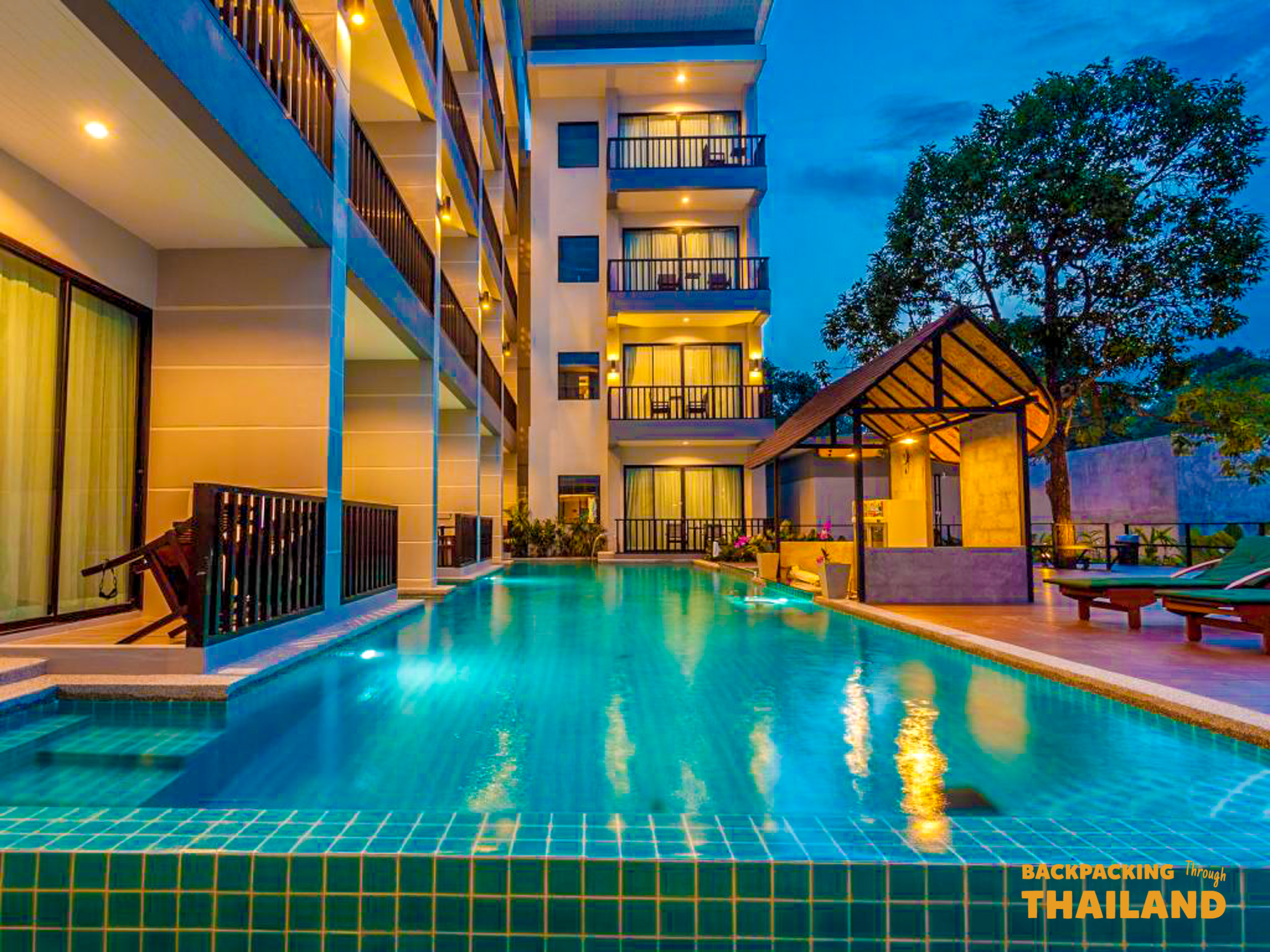 Night view of a resort swimming pool with palm trees and modern buildings reflected in the water, Day 9 accommodation