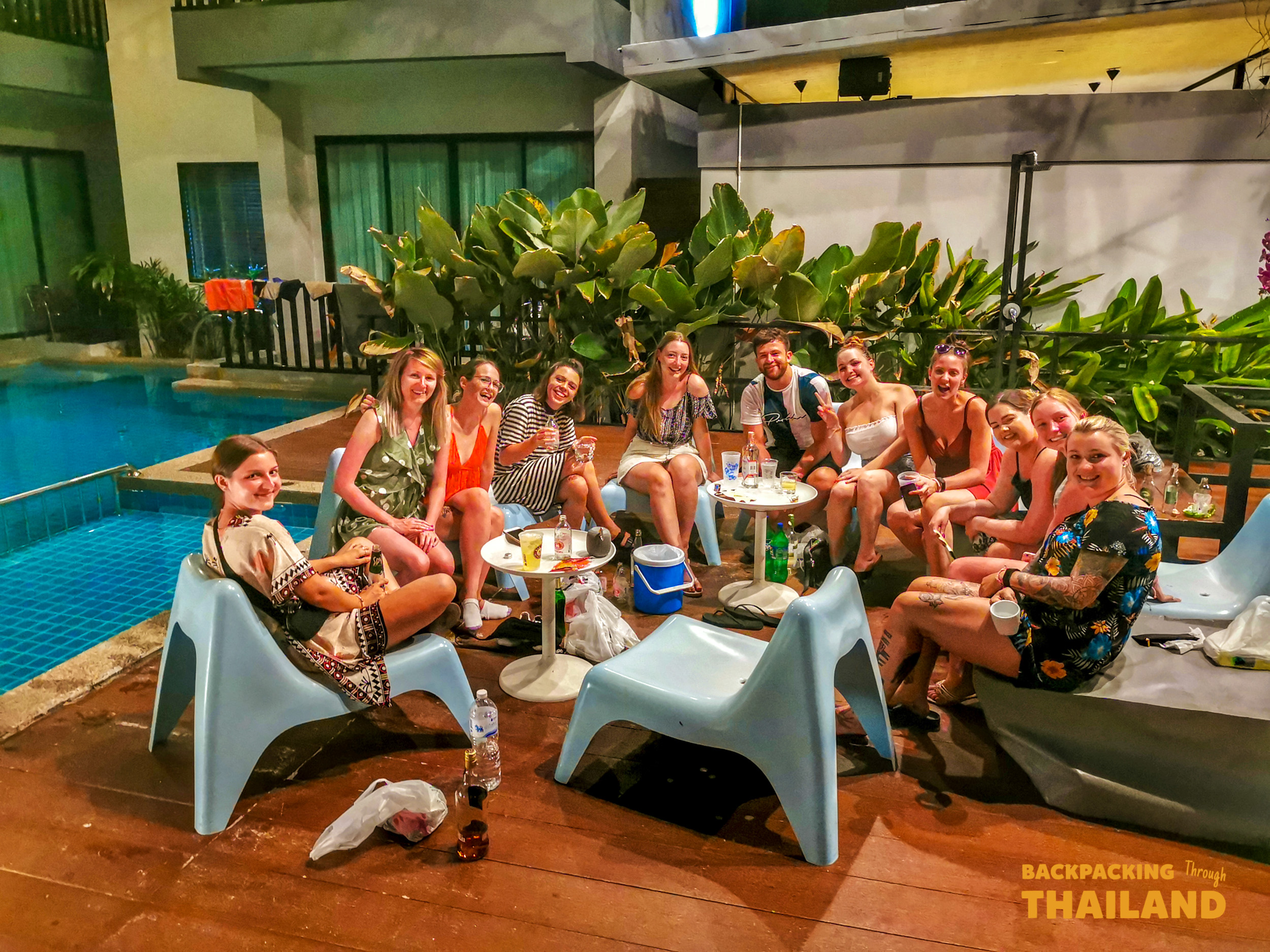 Large group of travellers dining together at a long outdoor table by the pool, Day 9 accommodation