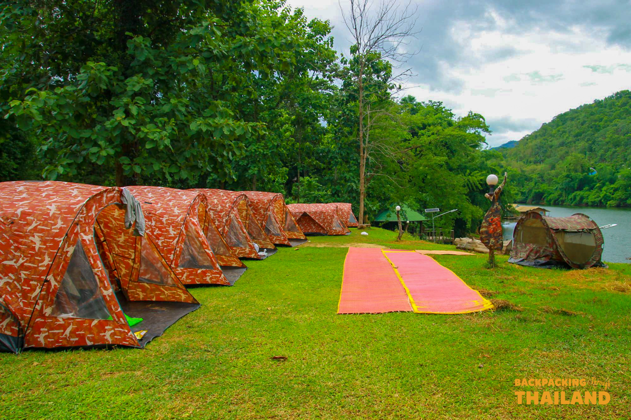Pathway with red stepping stones leading to cabins at the riverside campsite
