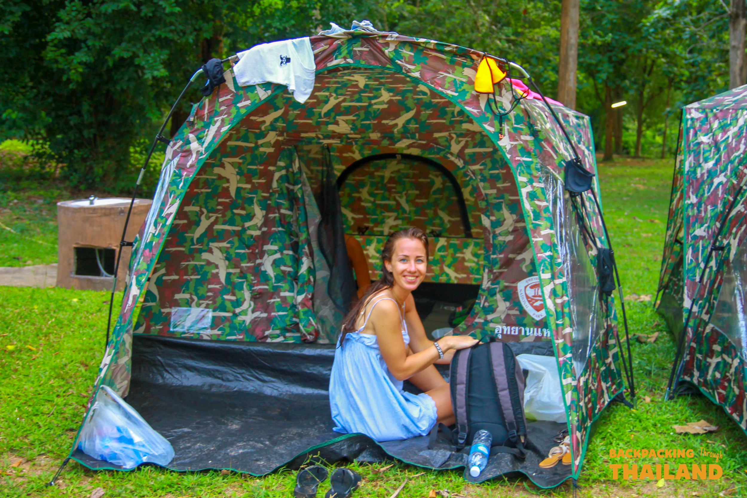 Backpacker relaxing inside a camouflaged tent at the riverside campsite