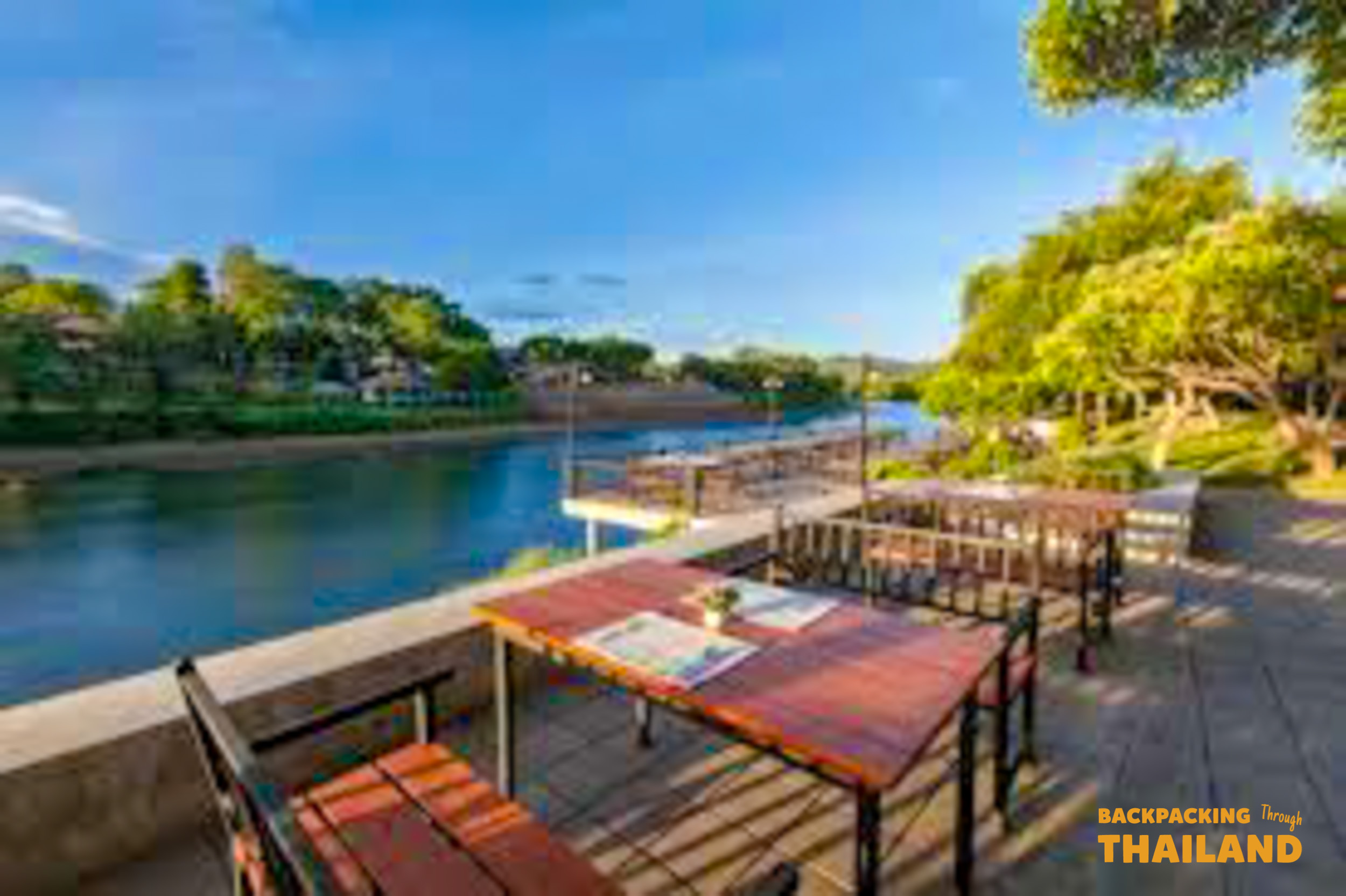 Dining deck with tables and chairs overlooking a lake and lush hills