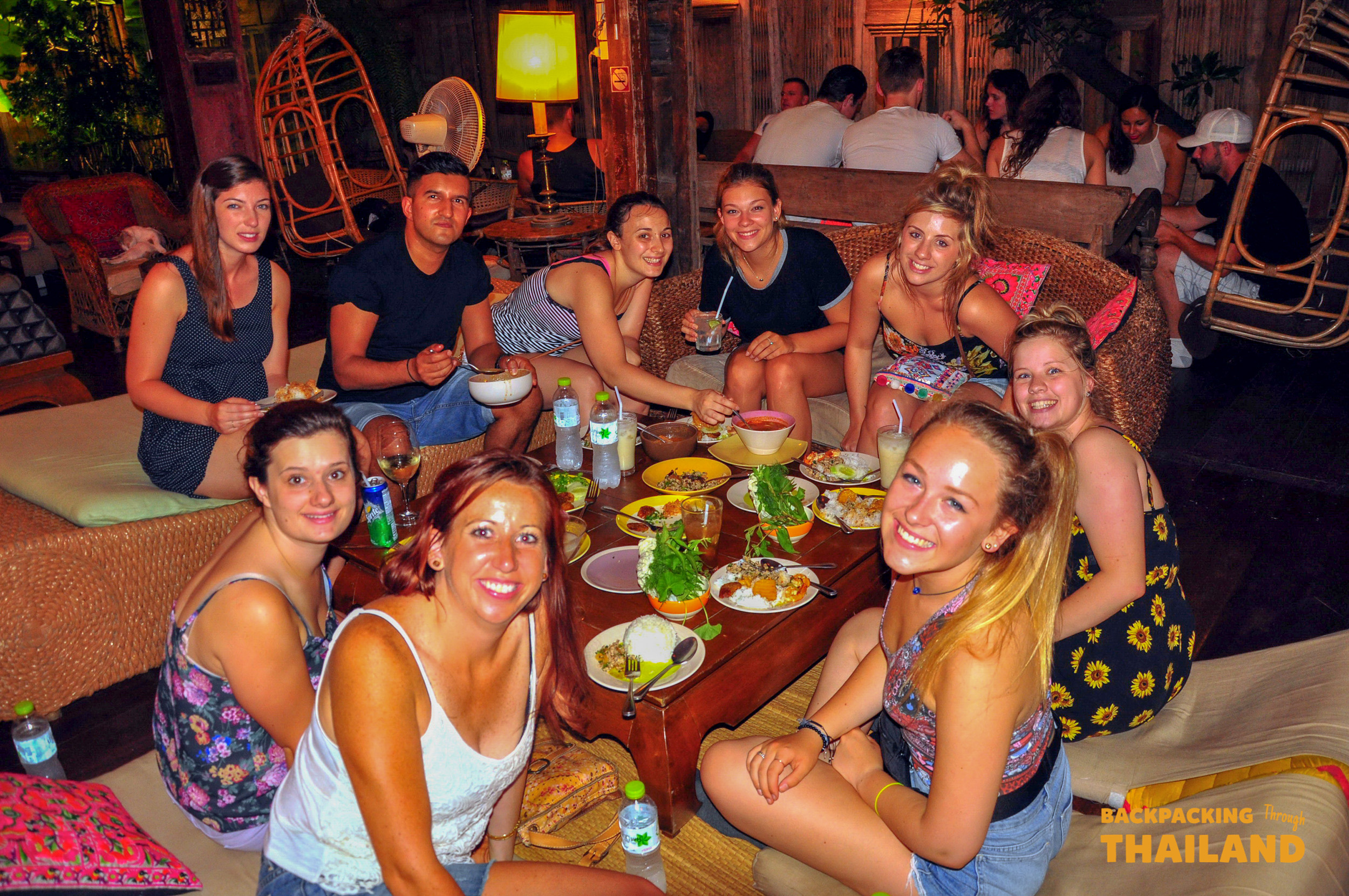 A happy group of backpackers enjoying a traditional Thai dinner together on Khao San Road, Bangkok.