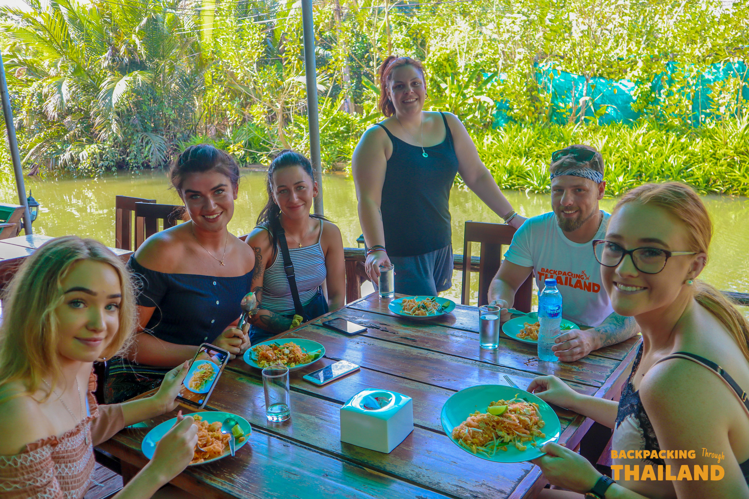 Backpacking group enjoying a home-cooked Thai meal together at the homestay