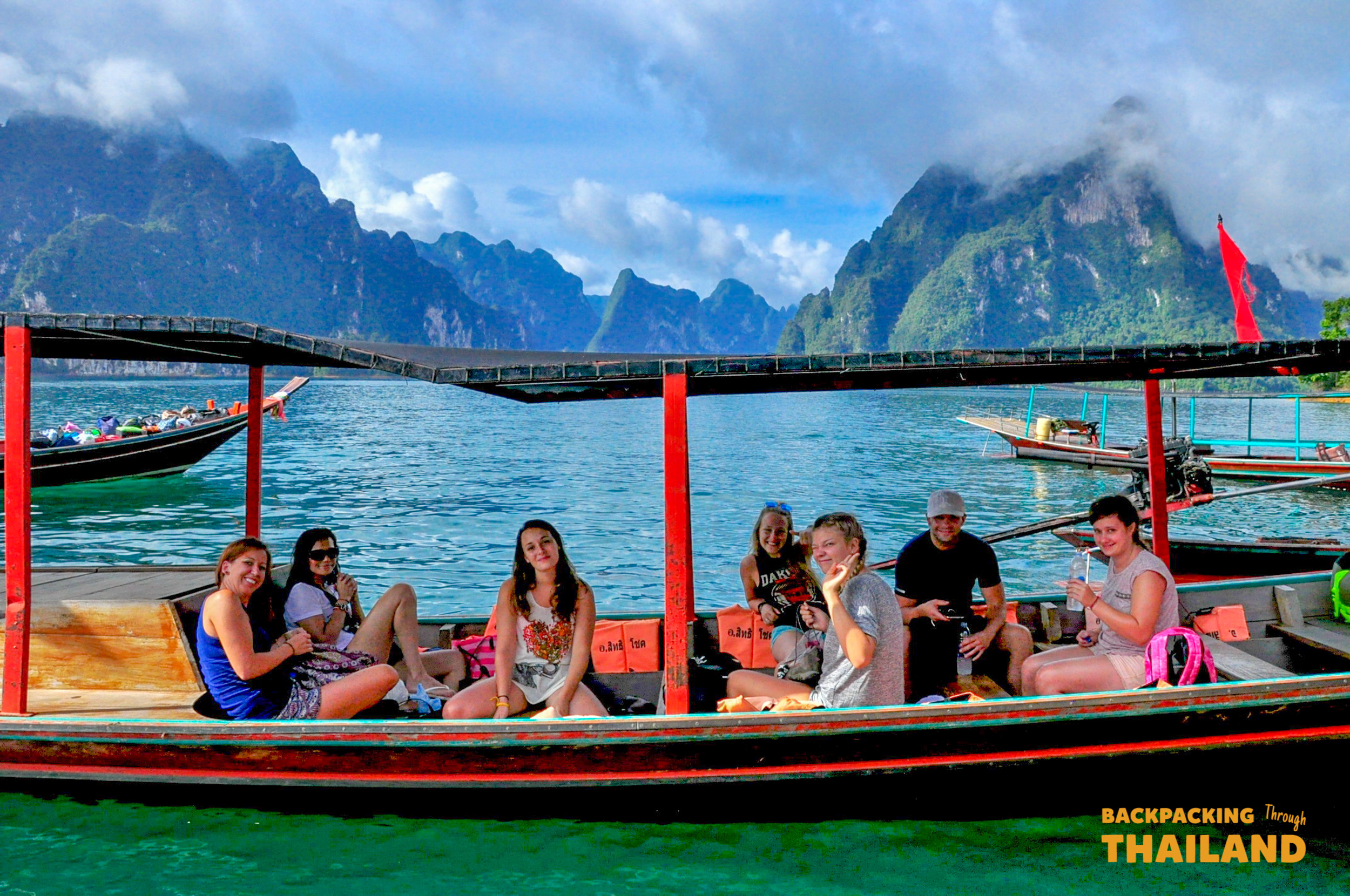 Travellers relax on a bamboo raft floating on a turquoise lake surrounded by mountains, Day 8 activity