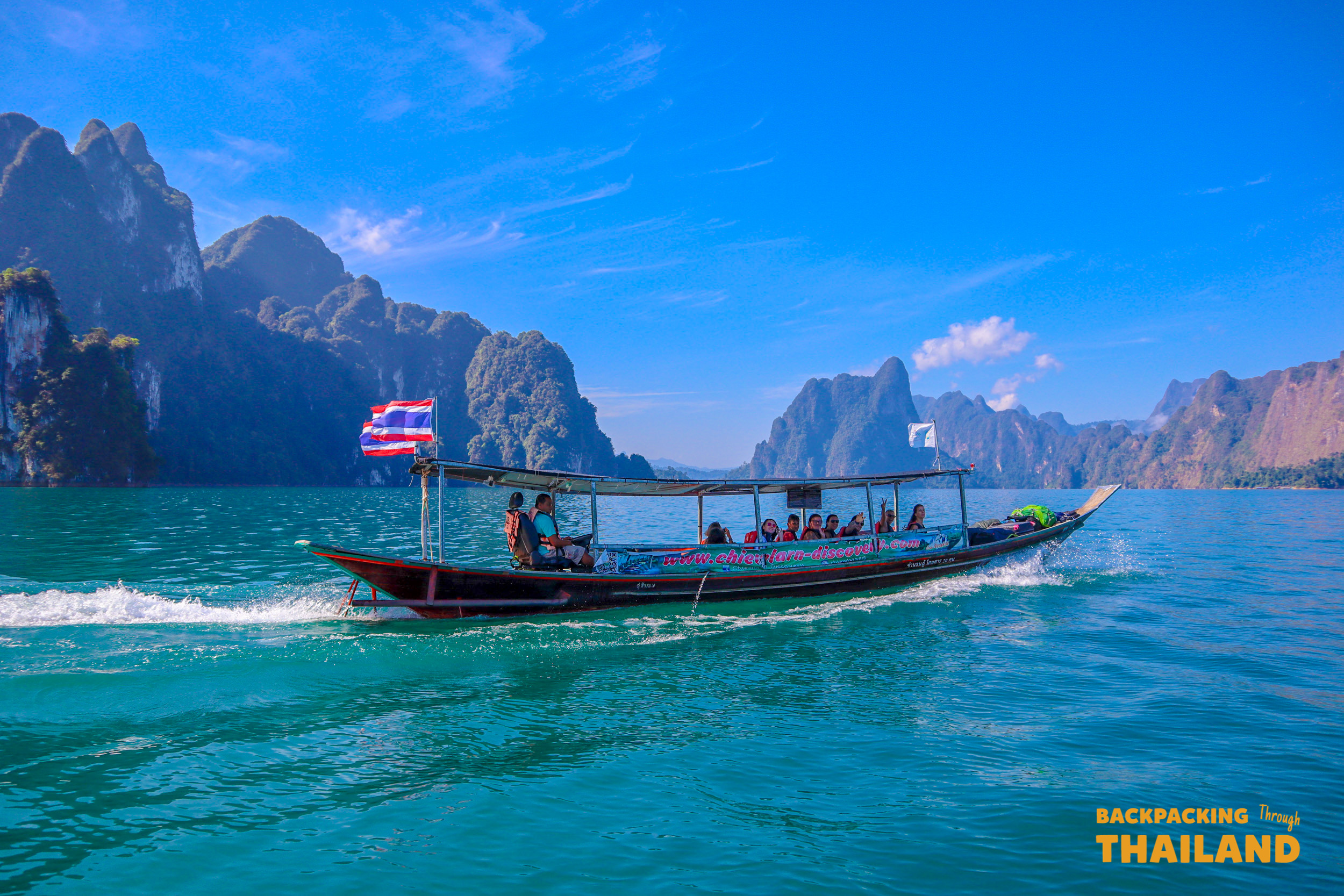 Longtail boat cruising through emerald waters against towering limestone cliffs, Day 8 activity