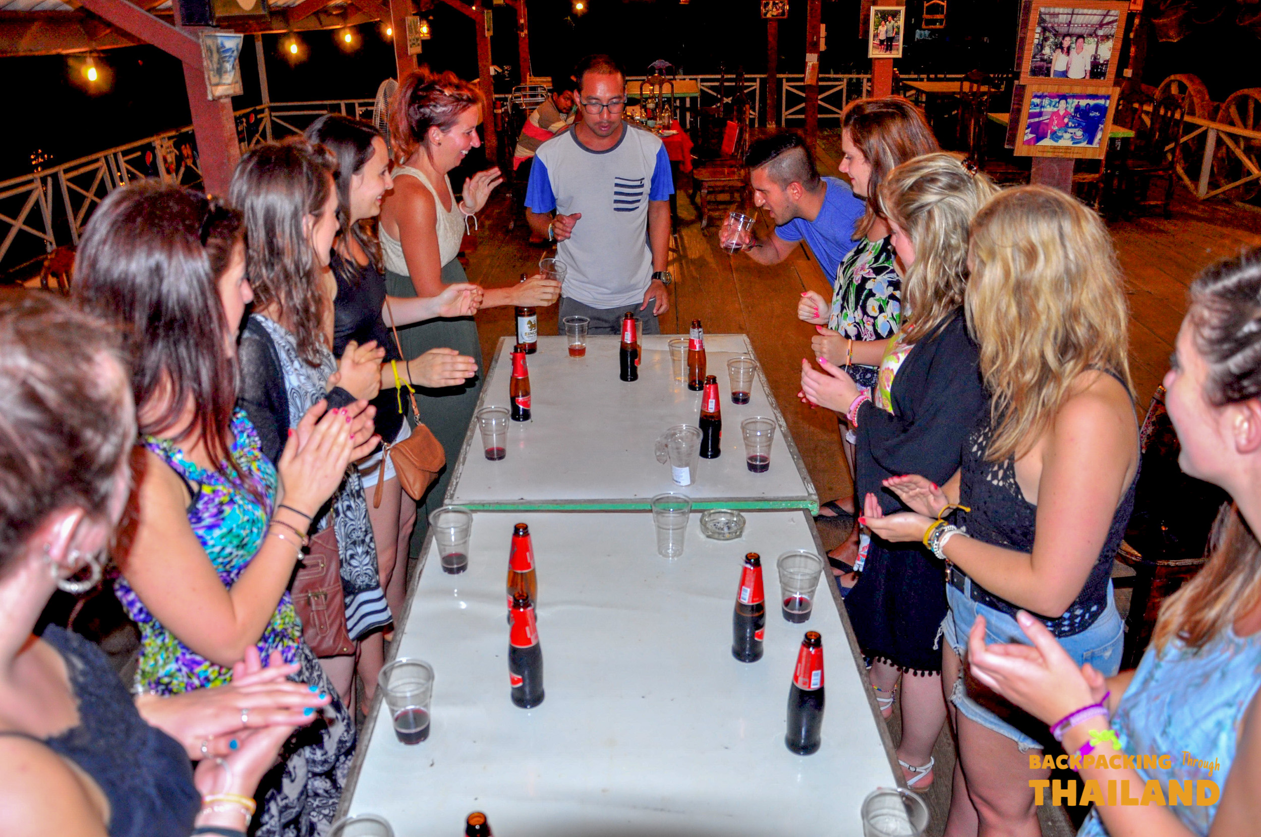 Group of travellers sharing drinks and snacks around a long table in a lively restaurant, Day 8 activity