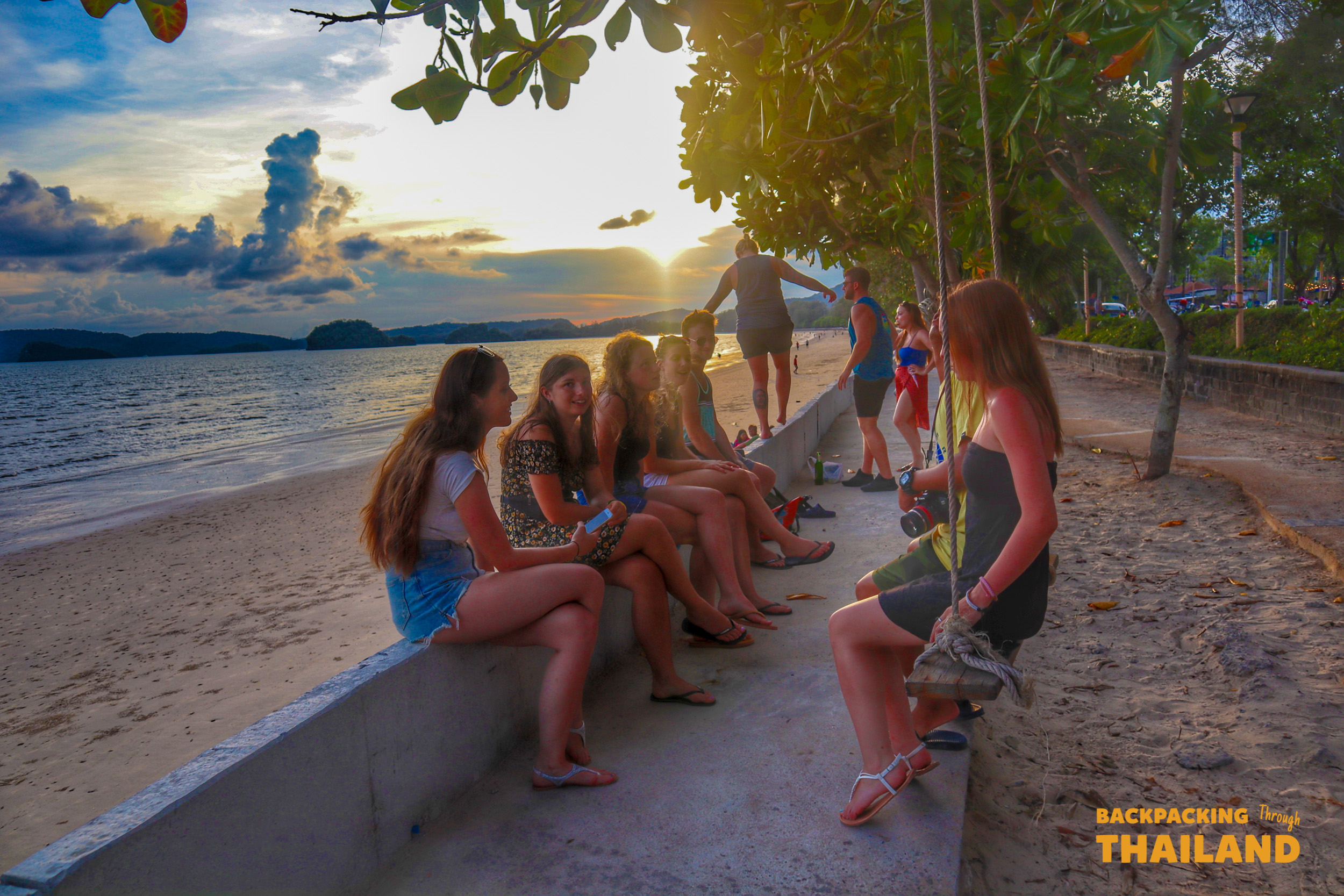 Relaxing together on a sandy beach at sunset with trees and water in the background, Day 9 activity