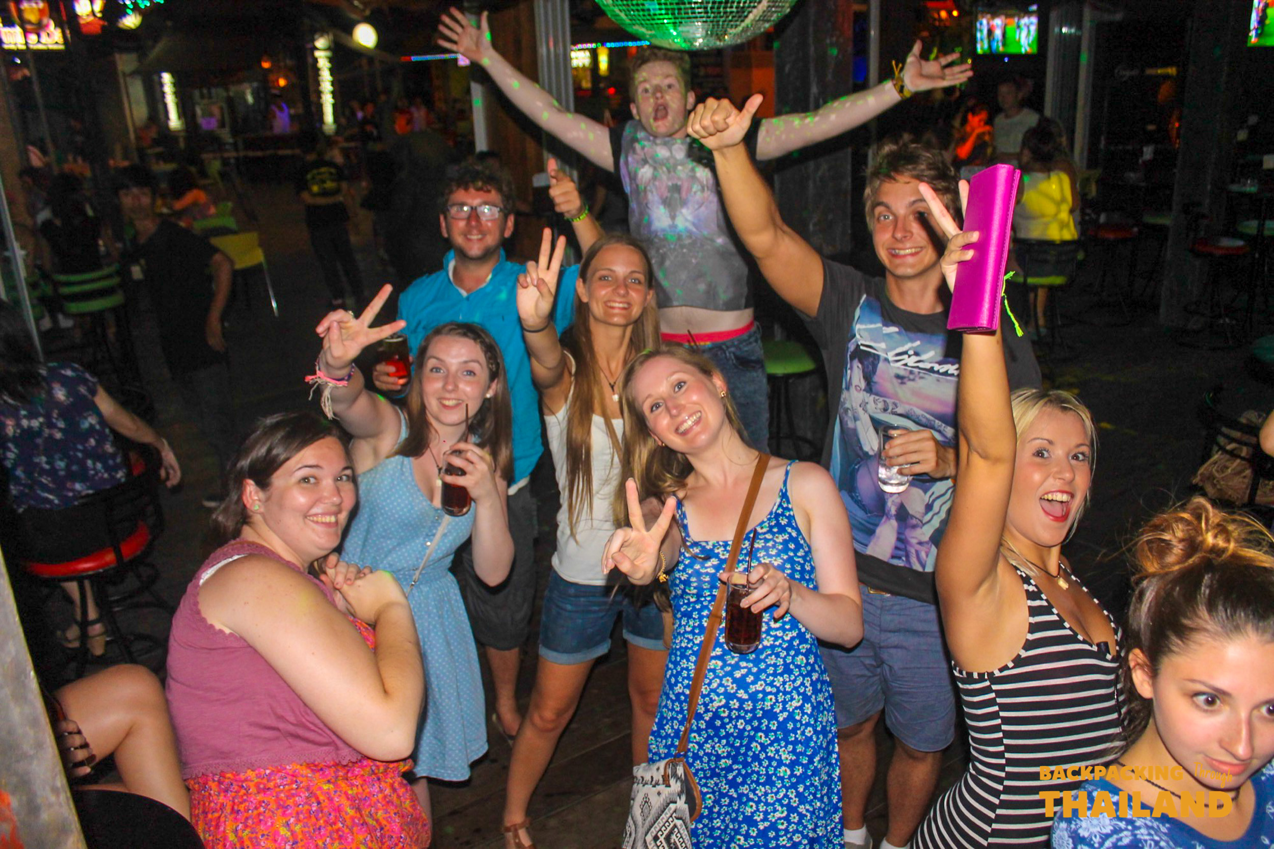 Friends dancing and celebrating at a lively nightclub with drinks and neon lights, Day 9 activity