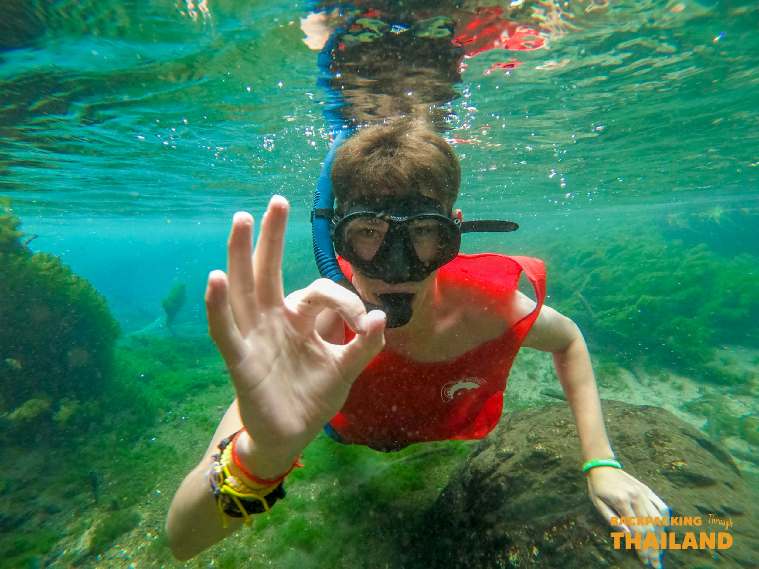 Snorkeler giving an OK sign underwater with coral reef and turquoise water, Day 10 activity