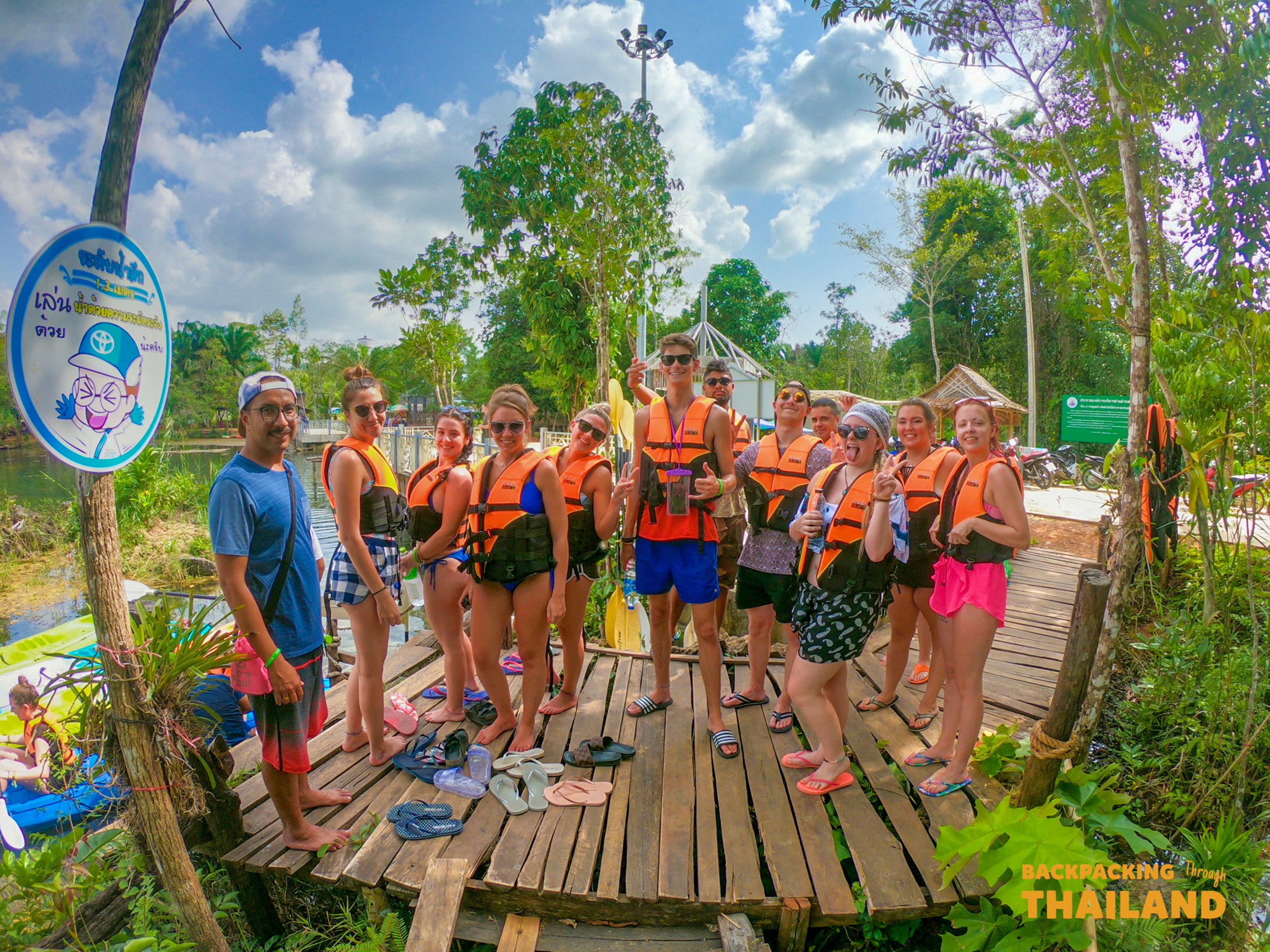 Group of travellers posing on a dock with kayaks on a turquoise lake, Day 10 activity