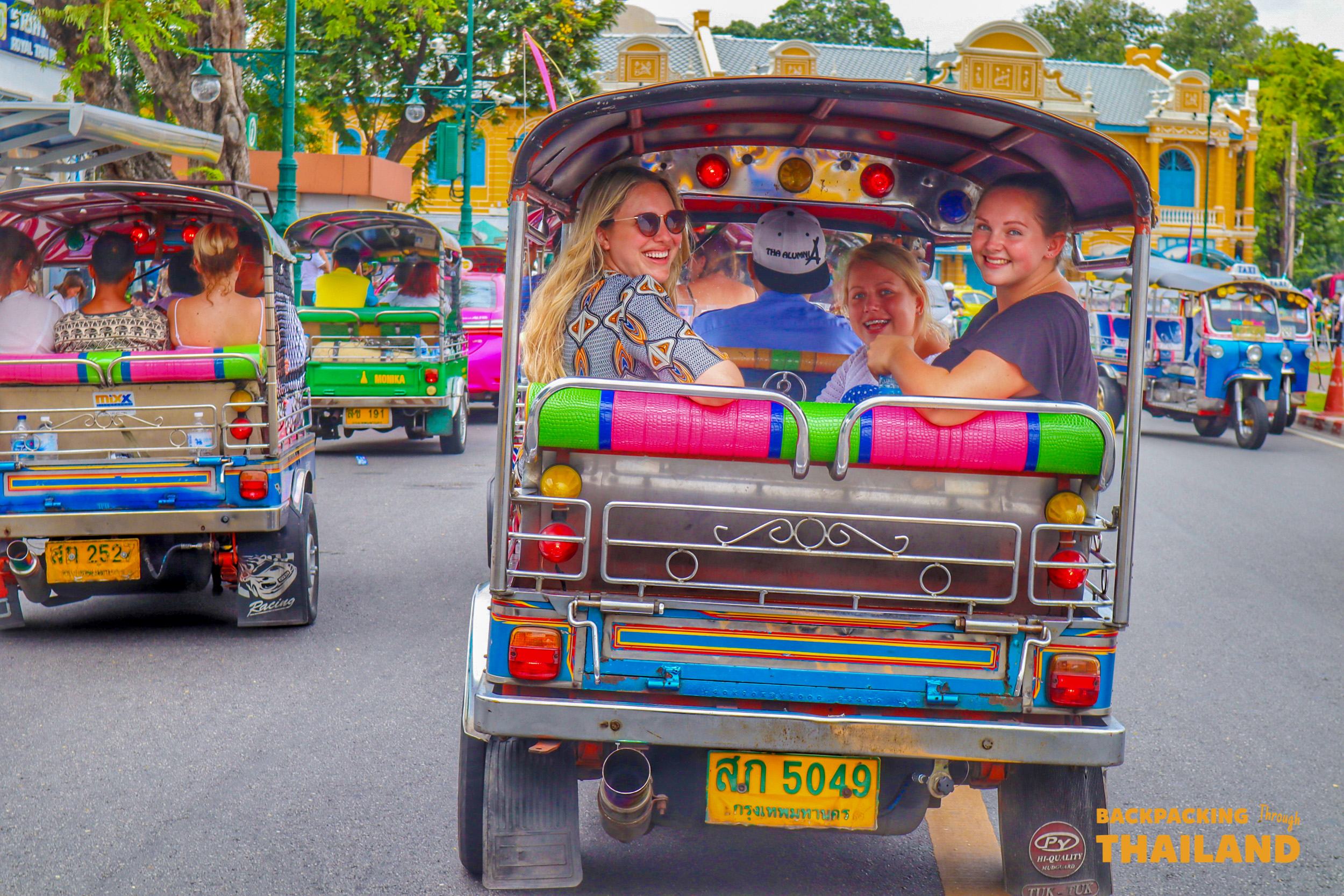 Happy backpackers enjoy a thrilling tuk-tuk ride through the bustling streets of Bangkok, Thailand.