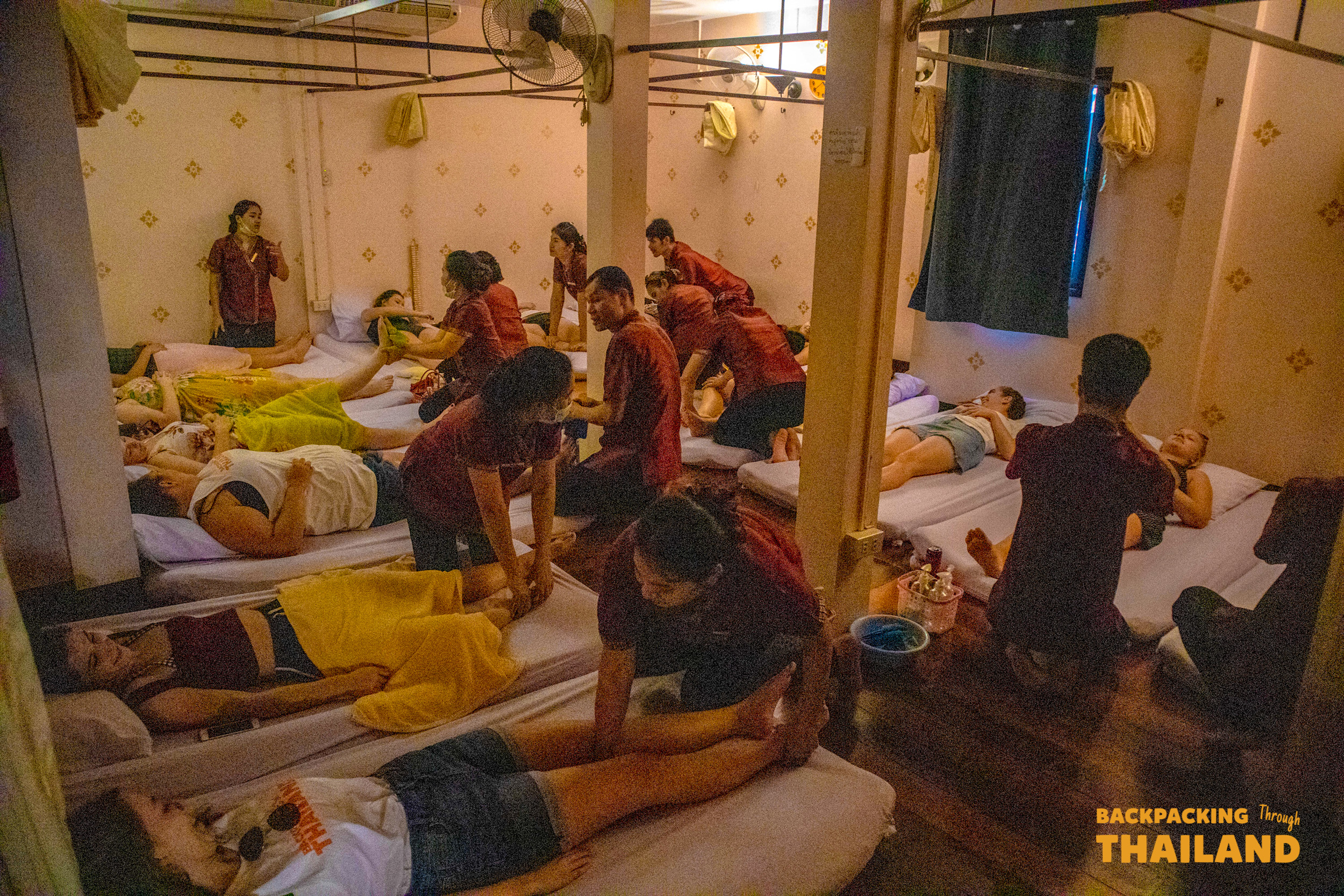 Backpacking Tour group receiving a relaxing traditional Thai massage in a calm setting.