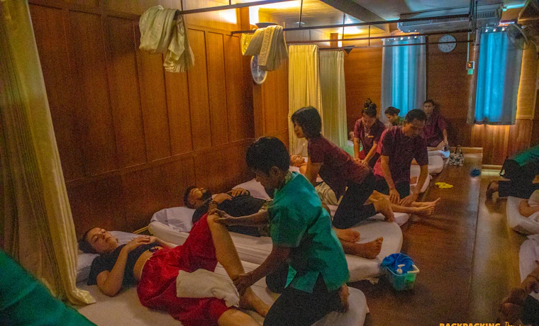 Travelers relax during a traditional Thai massage session in a peaceful, wood-paneled room in Bangkok.