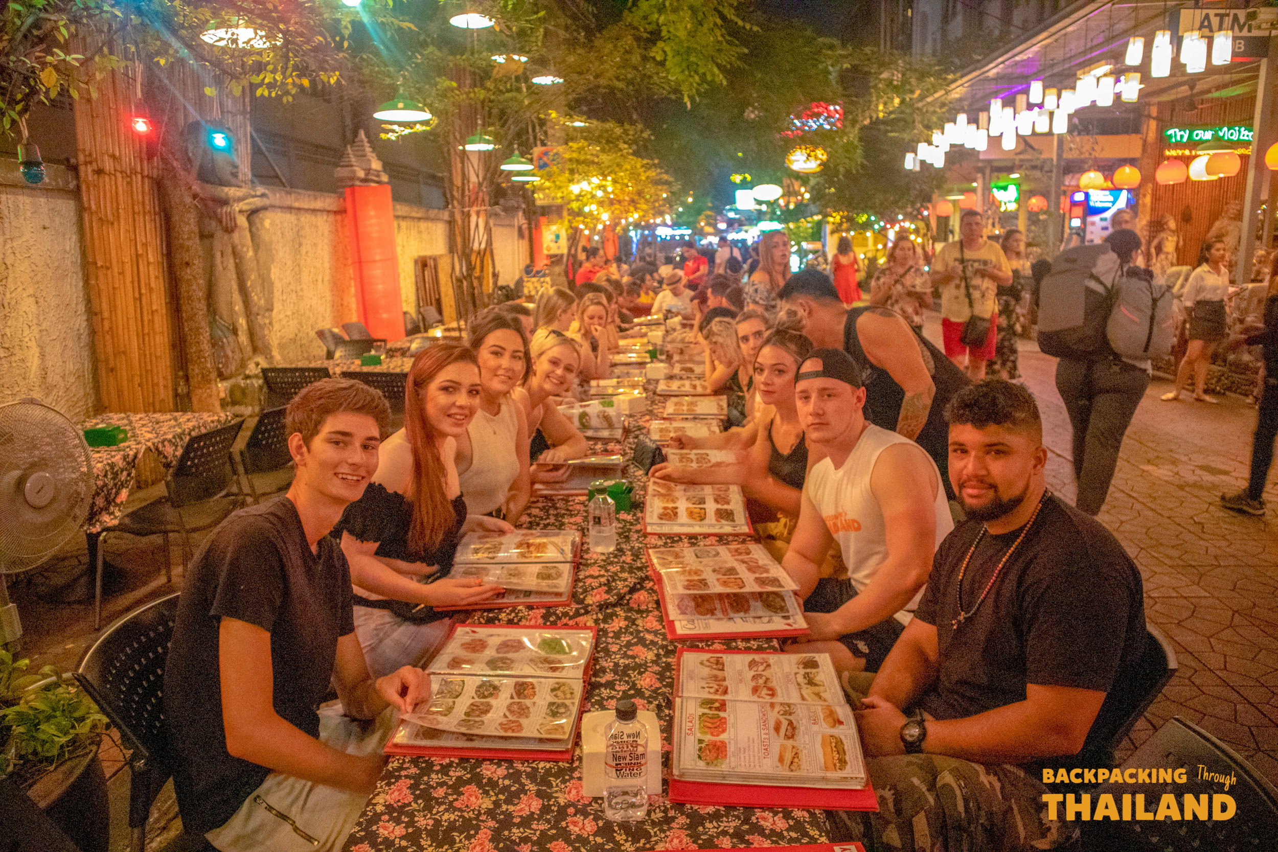 Evening street dining scene on Khao San Road with bright neon lights and a busy atmosphere.