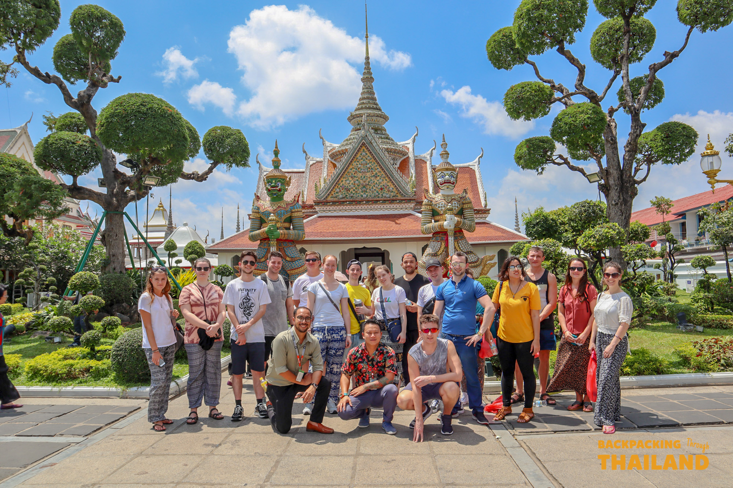Tour group smiling together in front of a decorated temple entrance in Bangkok.