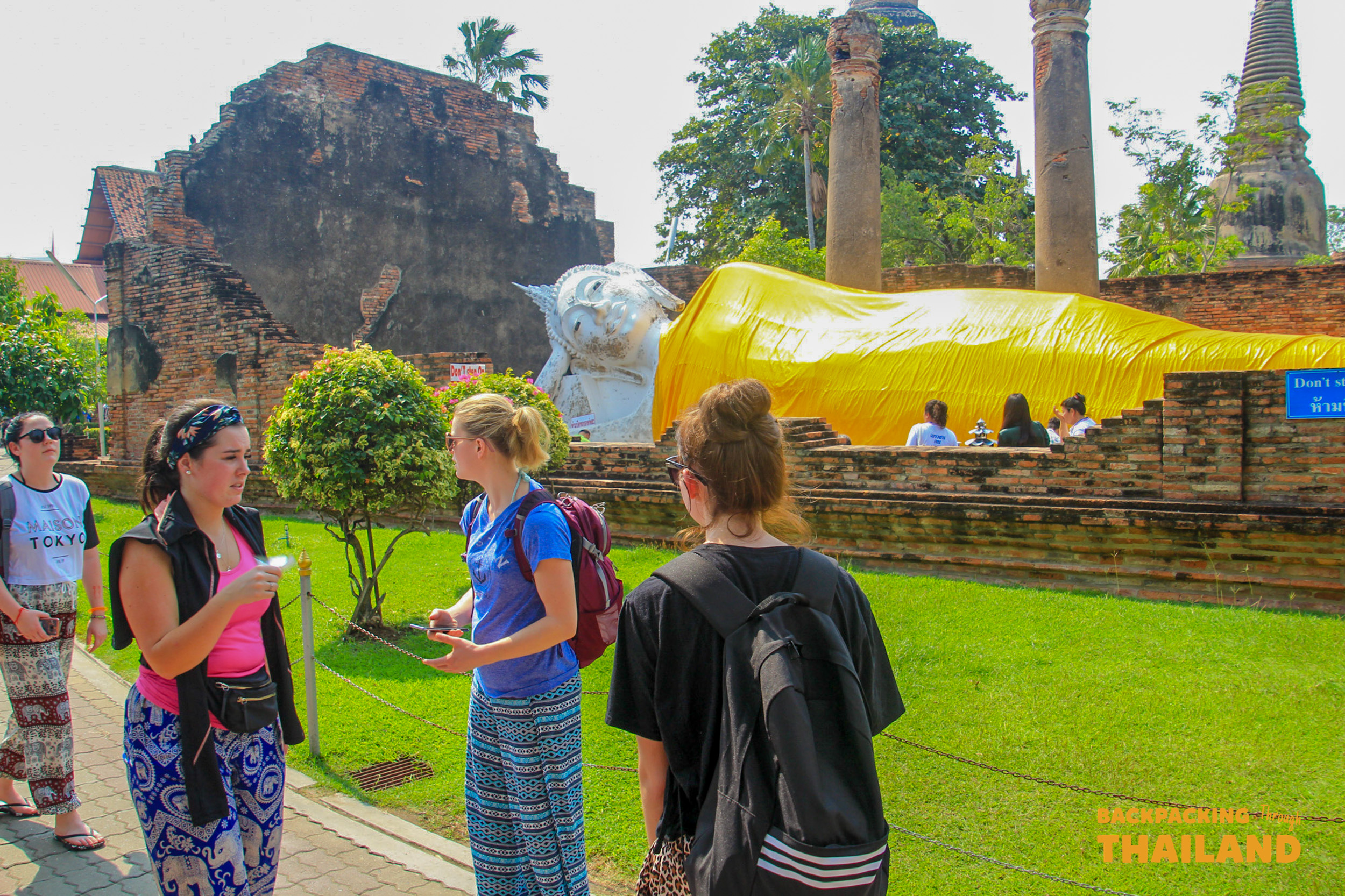 Tourists admire the giant reclining Buddha statue at the ancient ruins of Ayutthaya, Thailand.