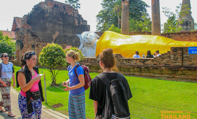 Tourists admire the giant reclining Buddha statue at the ancient ruins of Ayutthaya, Thailand.