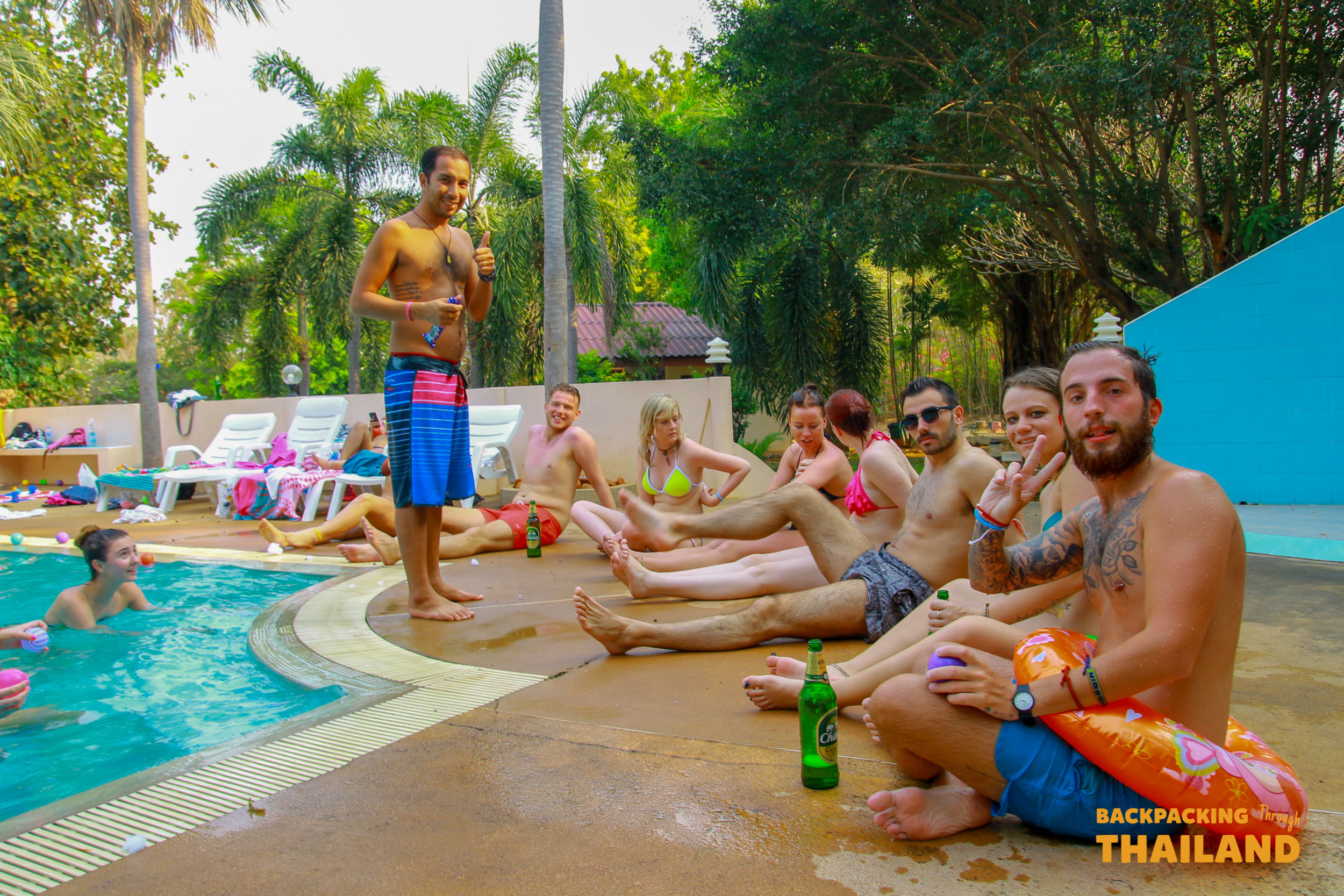 Friends enjoy a lively poolside party and drinking games at a resort in Singburi, Thailand.