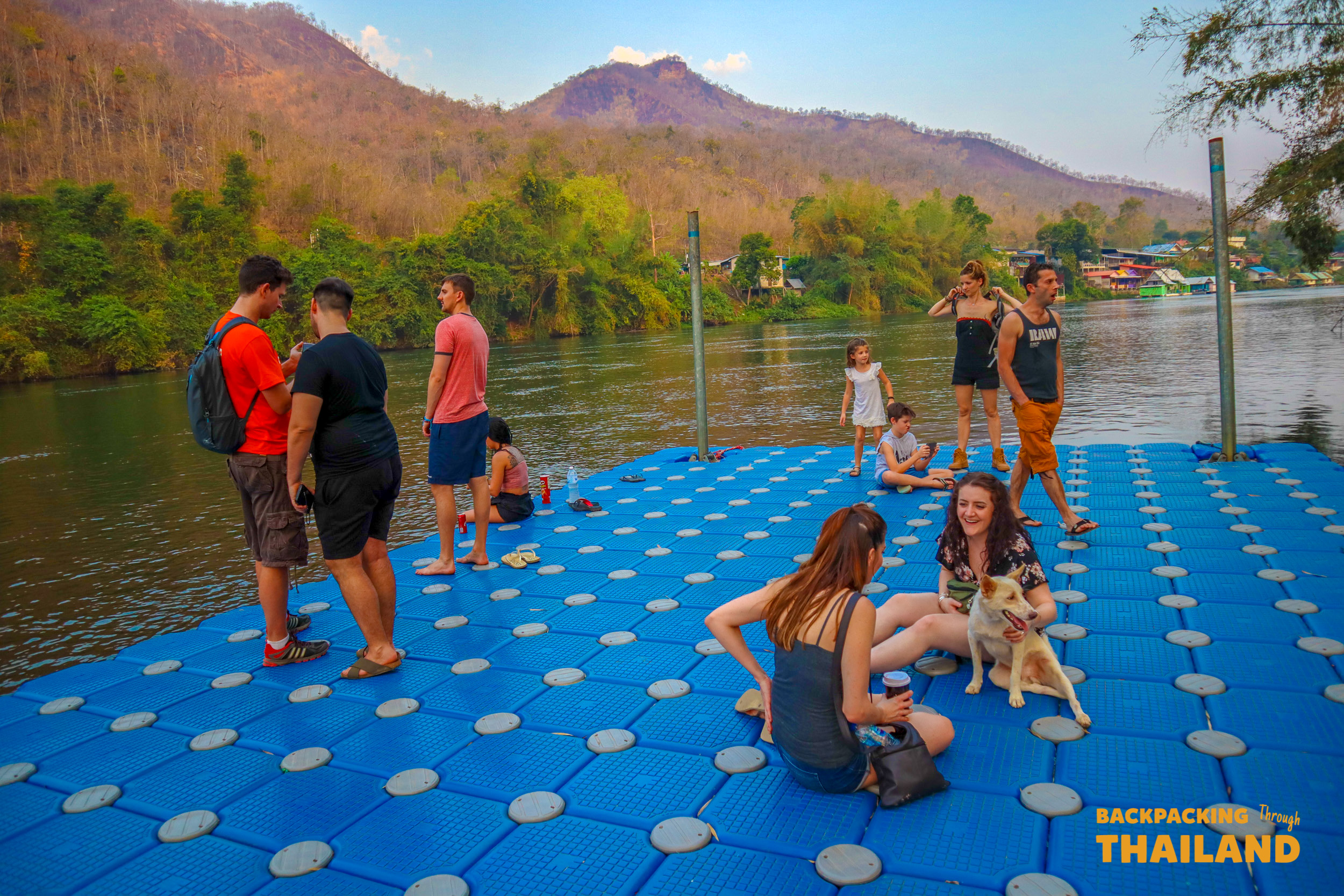Backpacking group standing on a floating blue walkway with mountains in the background