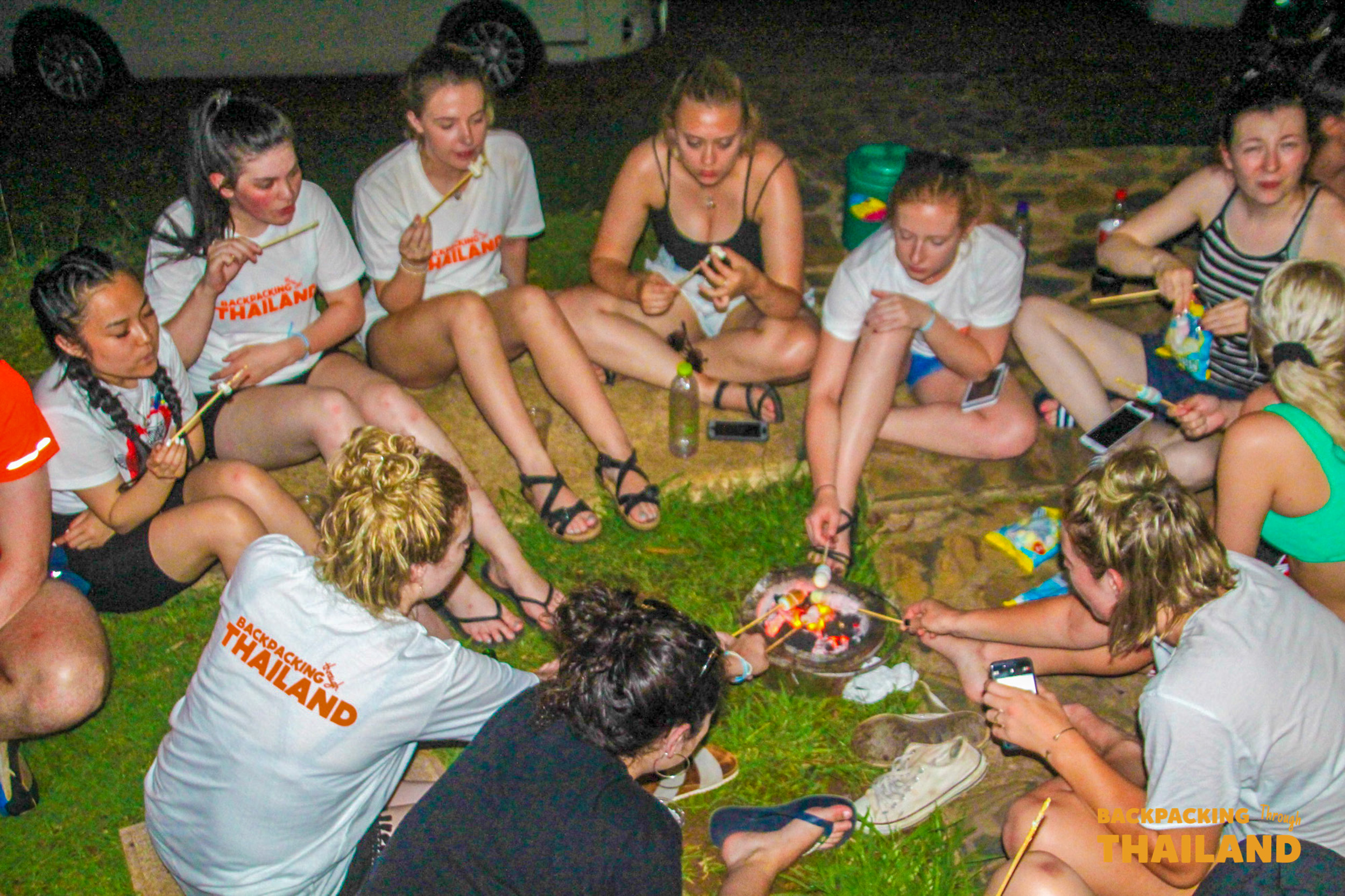 Backpacking group sitting on the ground sharing a communal meal during a picnic