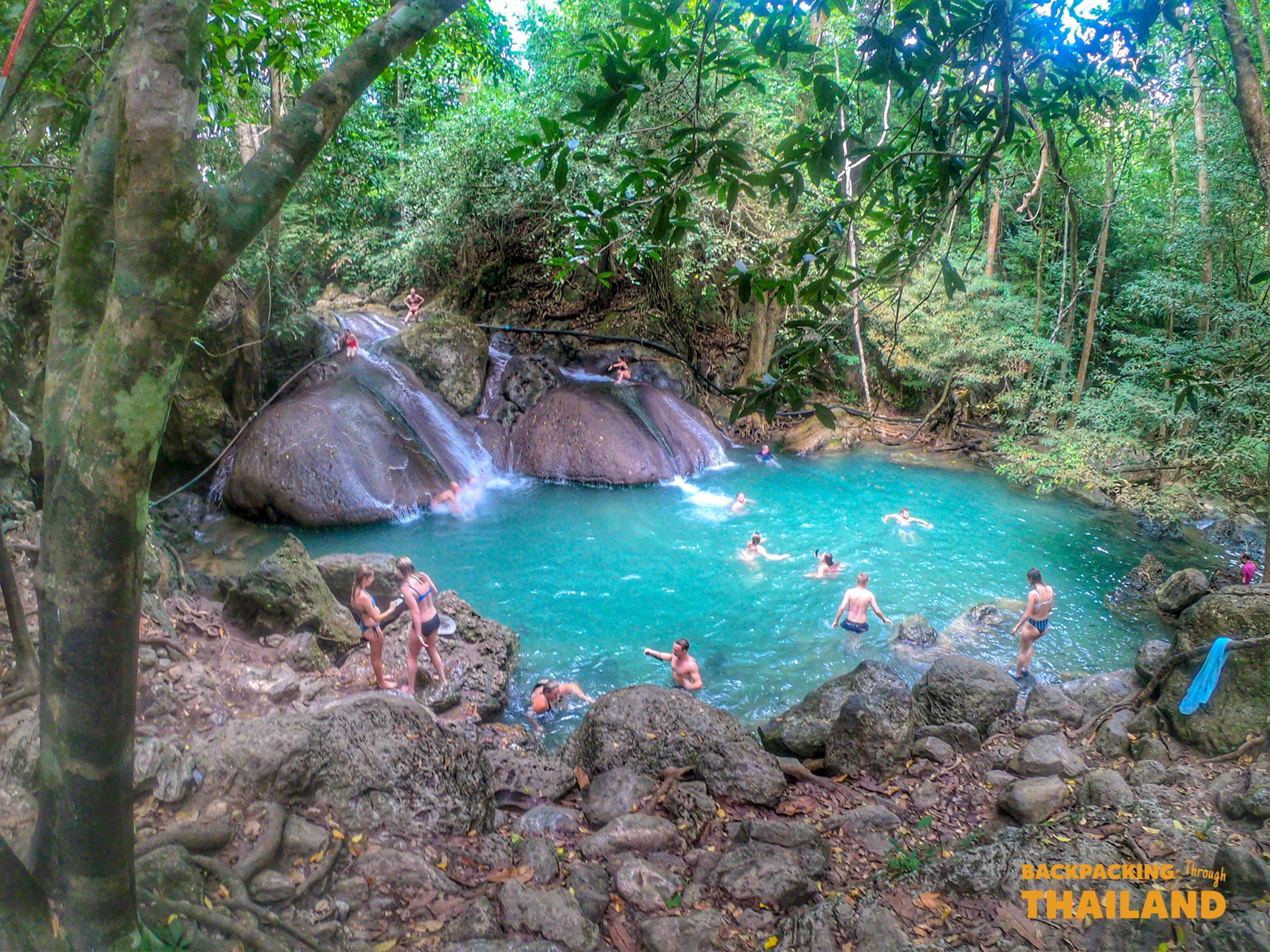 Scenic turquoise pool with rocks and lush forest at Erawan National Park
