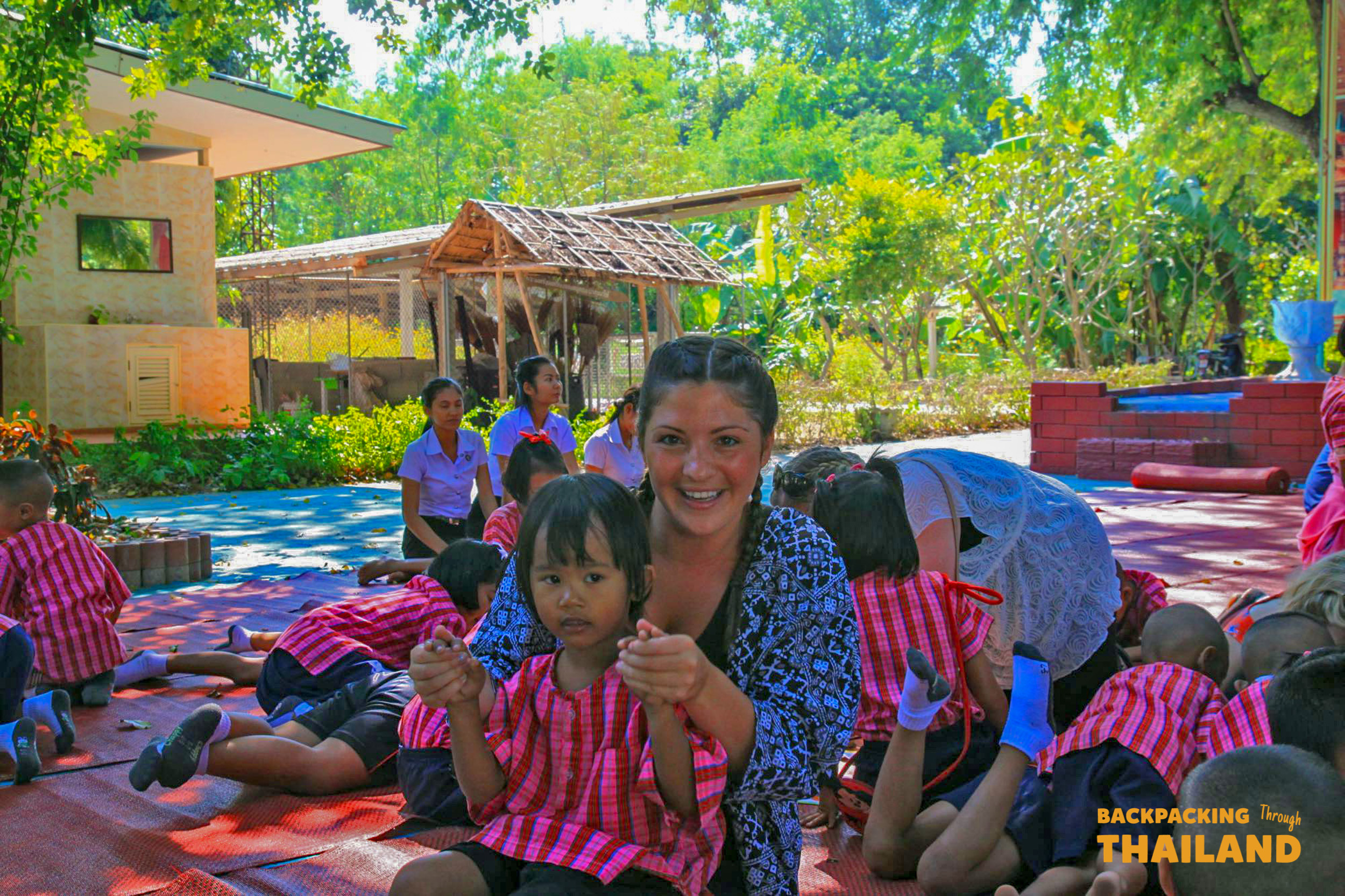 Backpacking travellers preparing food together at an outdoor cooking class with local women