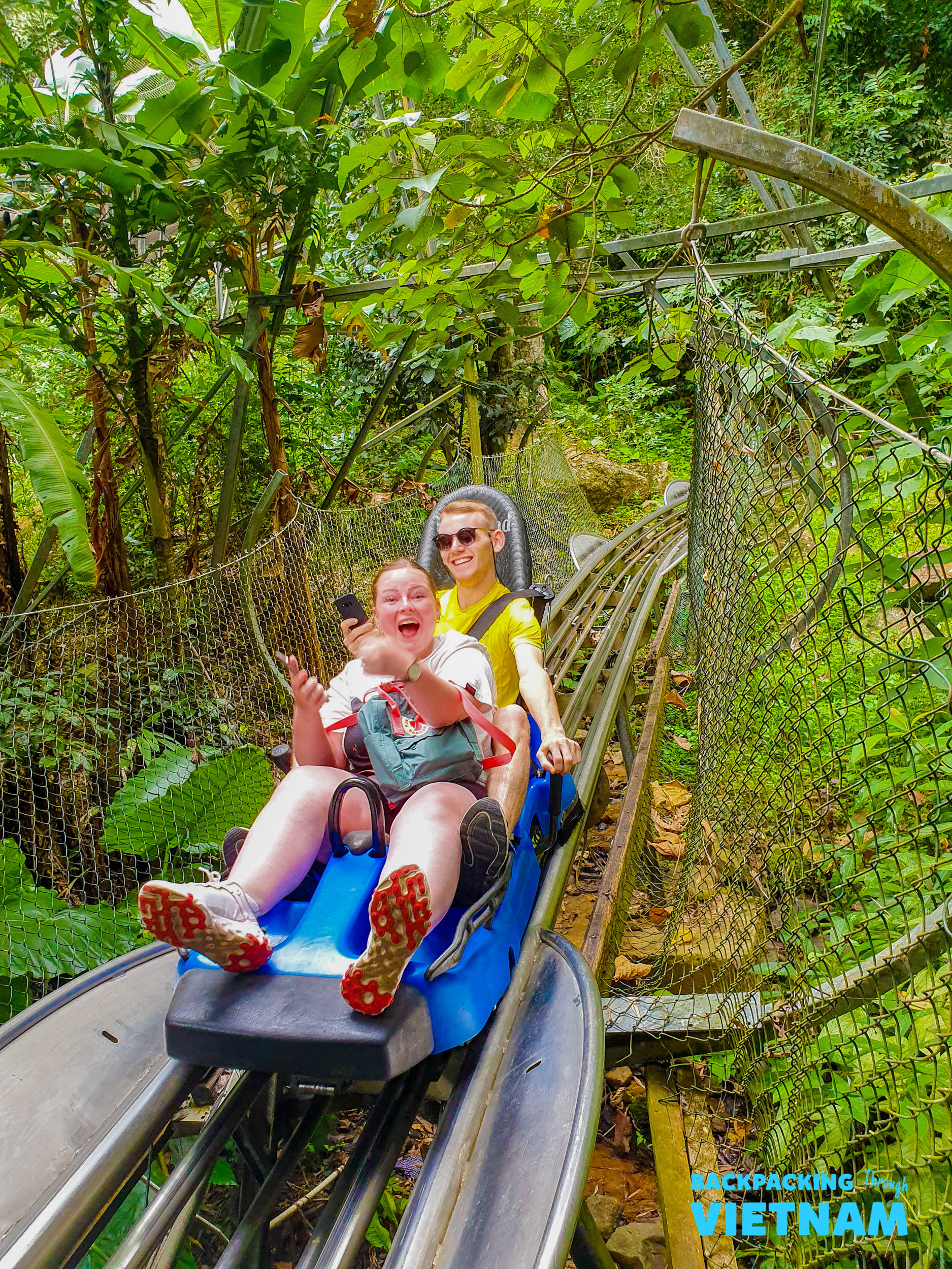 Backpacking group riding alpine coaster through Dalat forest
