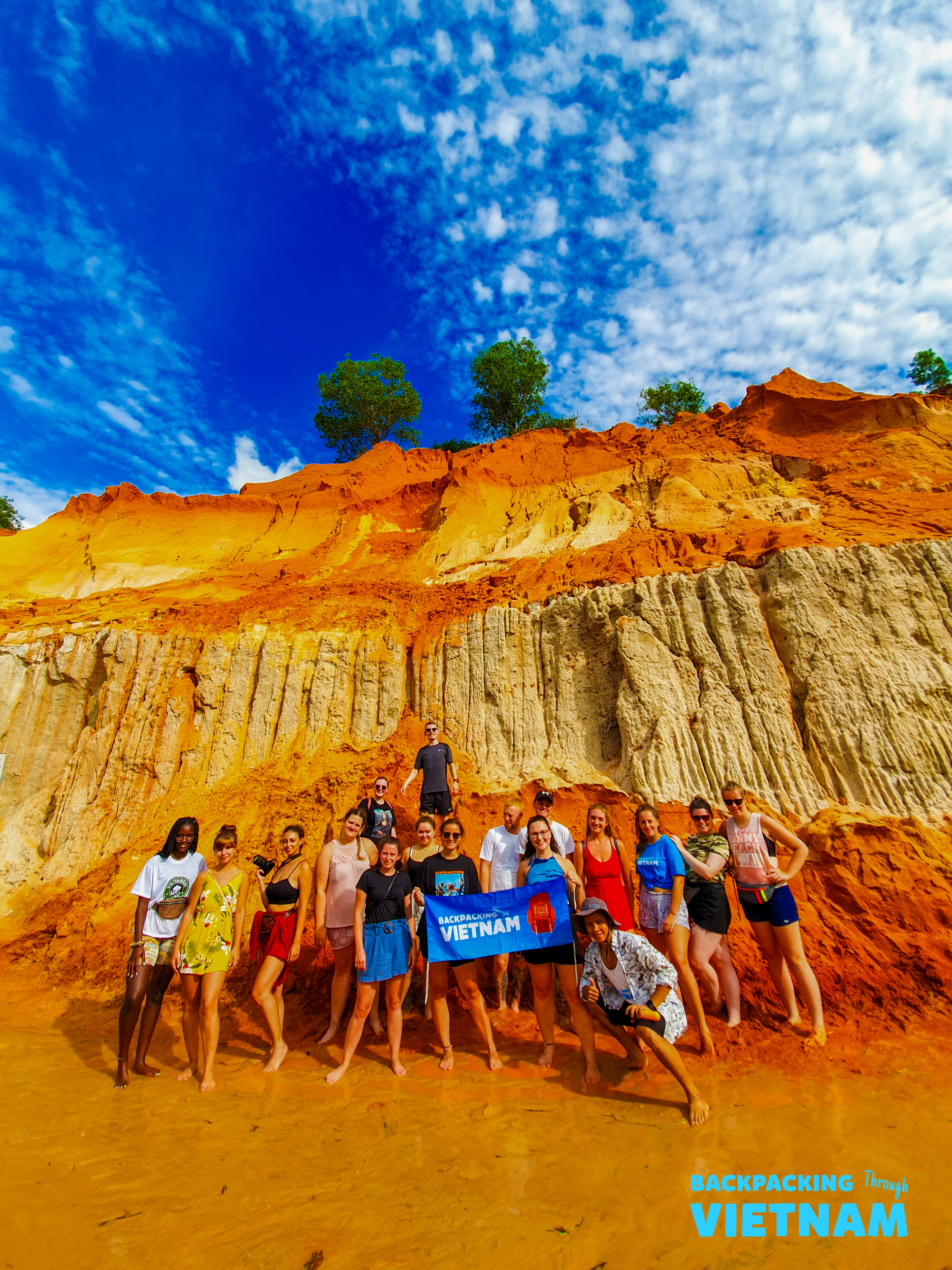 Backpackers posing by orange cliffs at Fairy Stream