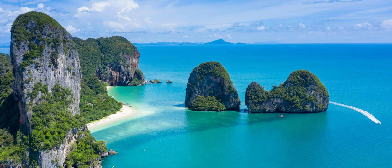 Towering limestone karsts, a pristine white sand beach, and clear turquoise waters in Krabi, Thailand.